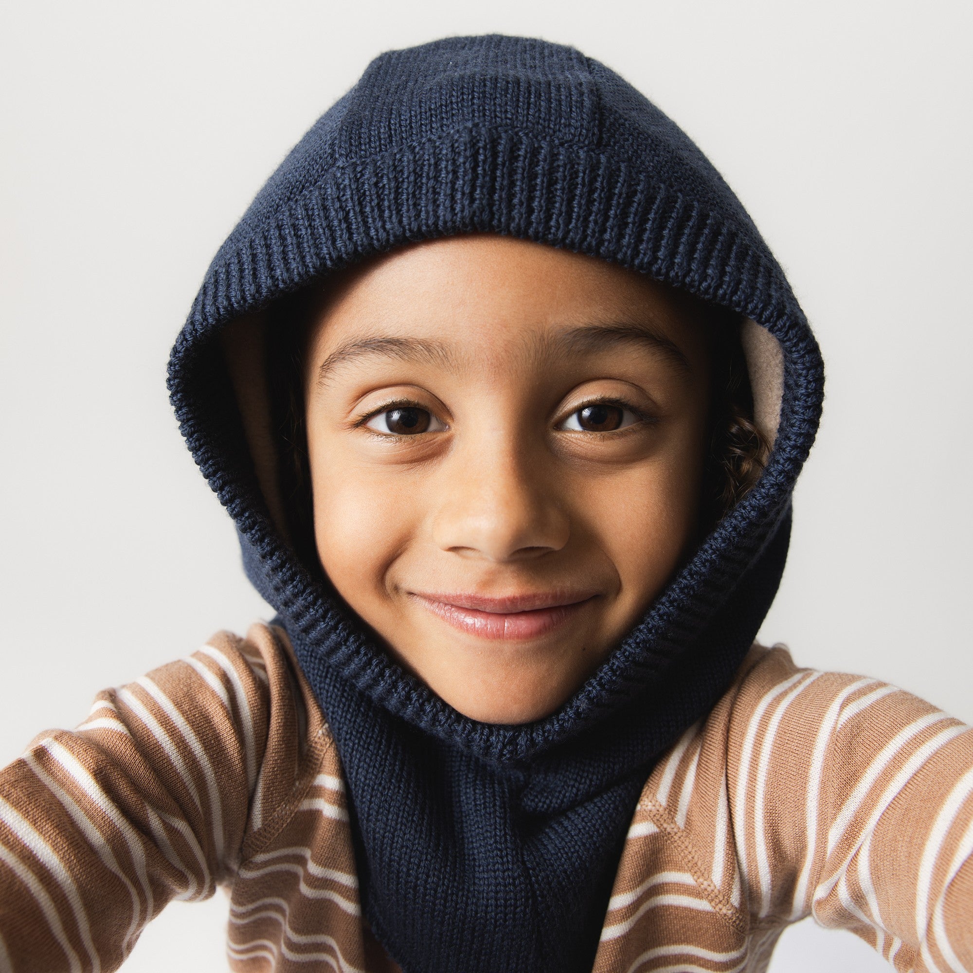 MATJORK fleece lined balaclava in navy blue merino wool, shown on a child, covering the head, neck and ears with full-coverage design and windstoppers at the ears.