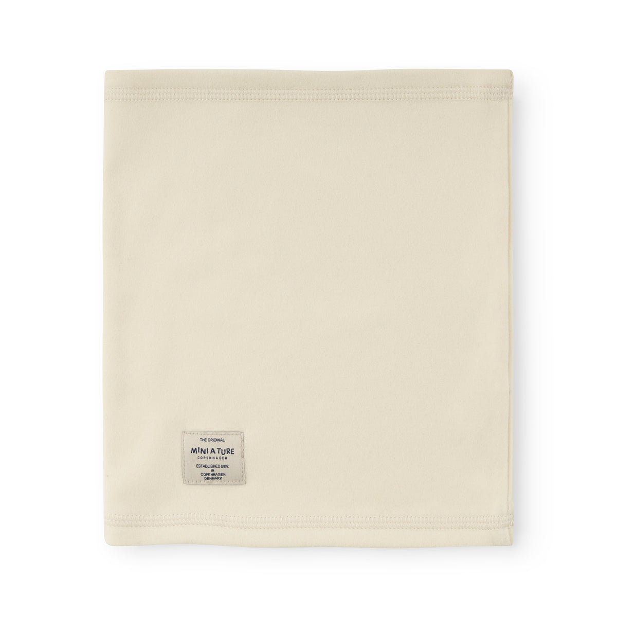 MATAKON Fleece-Halswärmer in zartem Creme, rechteckig gefaltet auf weißem Hintergrund, mit sichtbarem MINI A TURE Markenetikett und elastischen Nähten an beiden Rändern für flexiblen Tragekomfort.