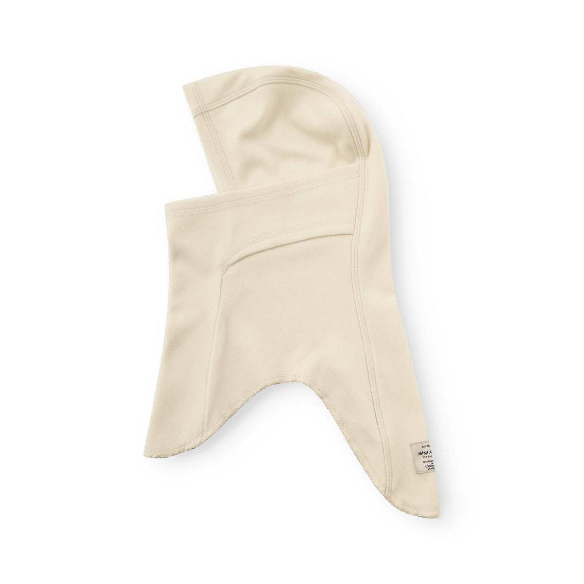 MATMANU Fleece-Sturmhaube in Angora Cream, flach auf weißem Hintergrund liegend, zeigt die Seitenansicht mit herunterklappbarem Mundschutz, sichtbaren Nähten und dem Mini A Ture Etikett am unteren Rand.