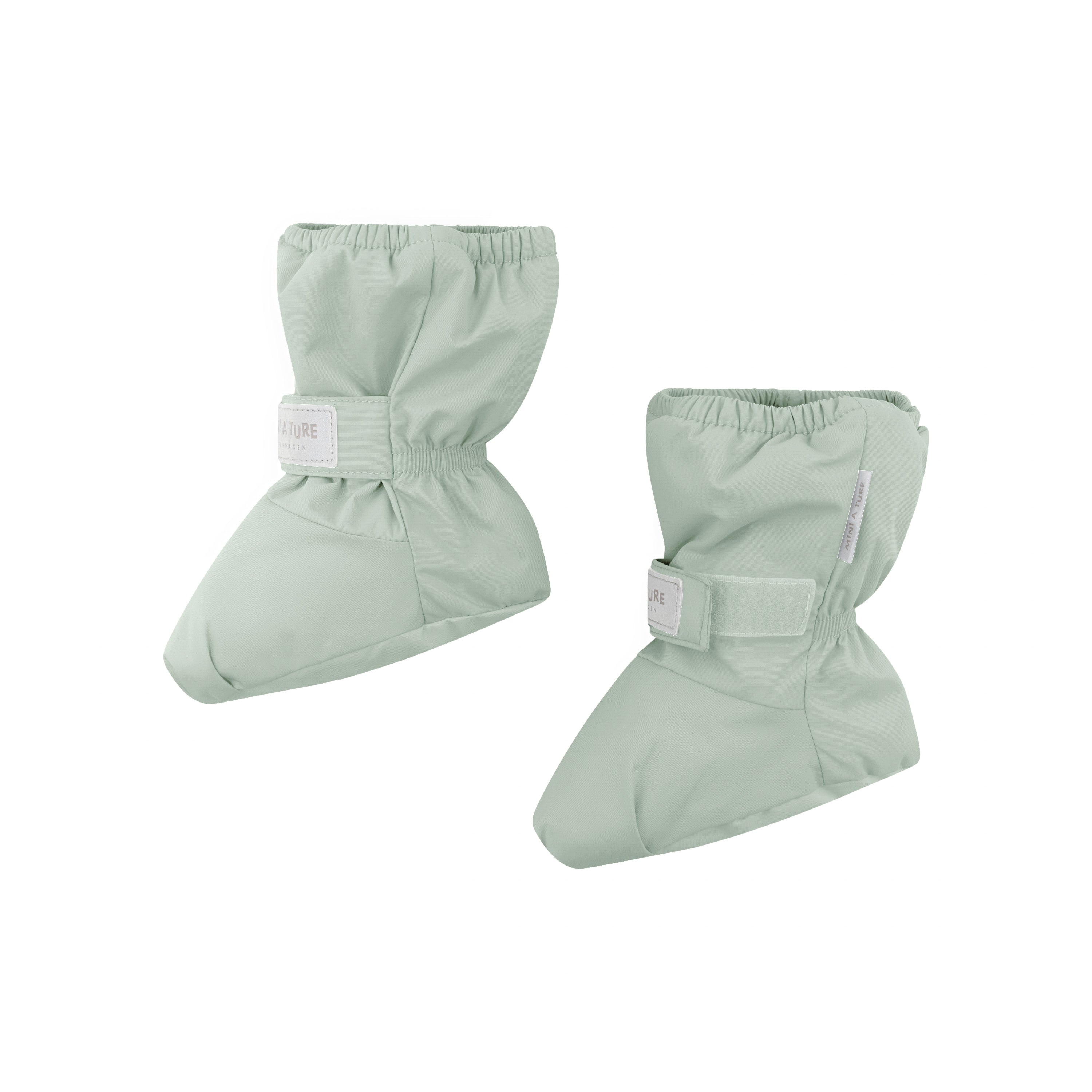 MATWINN waterproof baby outdoor socks in soft sage green photographed as a pair from the side, showing the adjustable velcro ankle strap with embossed MINI A TURE branding and the padded insulated construction for warmth during cold-weather pram journeys.