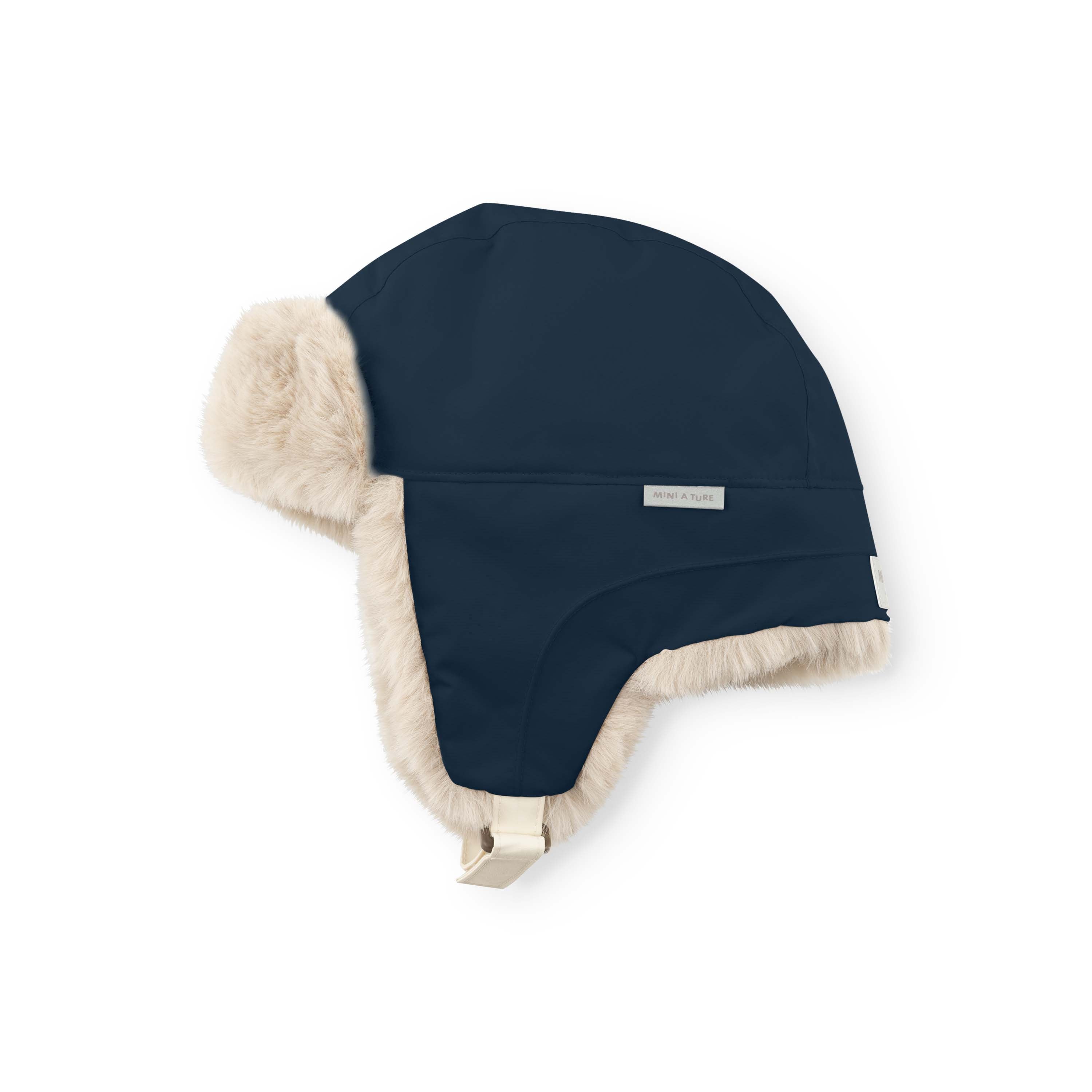 MATCRISTER children's trapper hat in dark navy with pale cream fleece ear flaps and lining, shown from a side angle with the velcro chin strap and reflective MINI A TURE label visible on the waterproof shell.