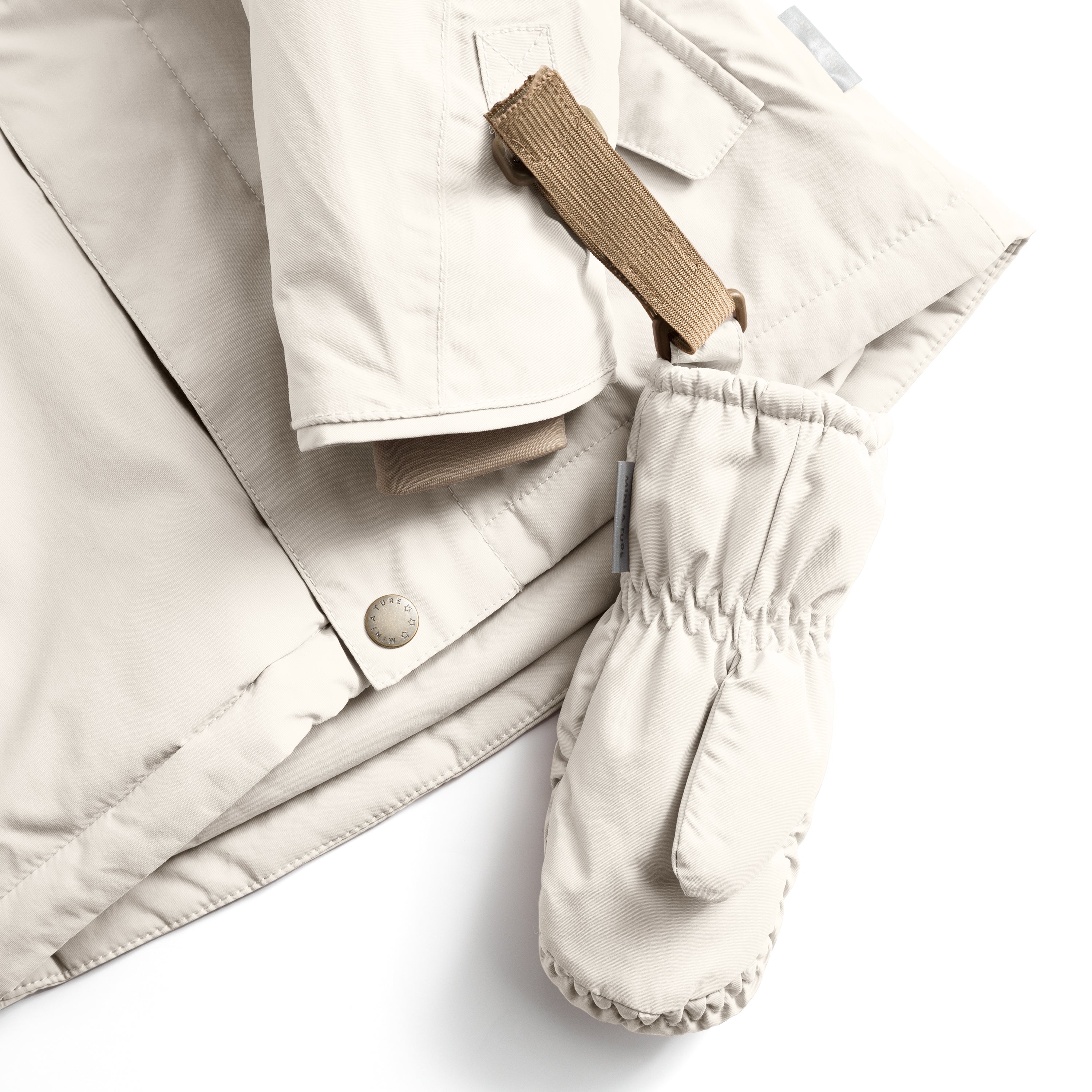 MATCORDT fleece lined mittens in pale cream shown attached to a matching jacket sleeve, with the beige velcro strap threaded through the D-loop fastening, the elastic gathered cuff sealing the wrist and the waterproof recycled polyamide shell visible alongside a press-stud jacket closure and taped seams.