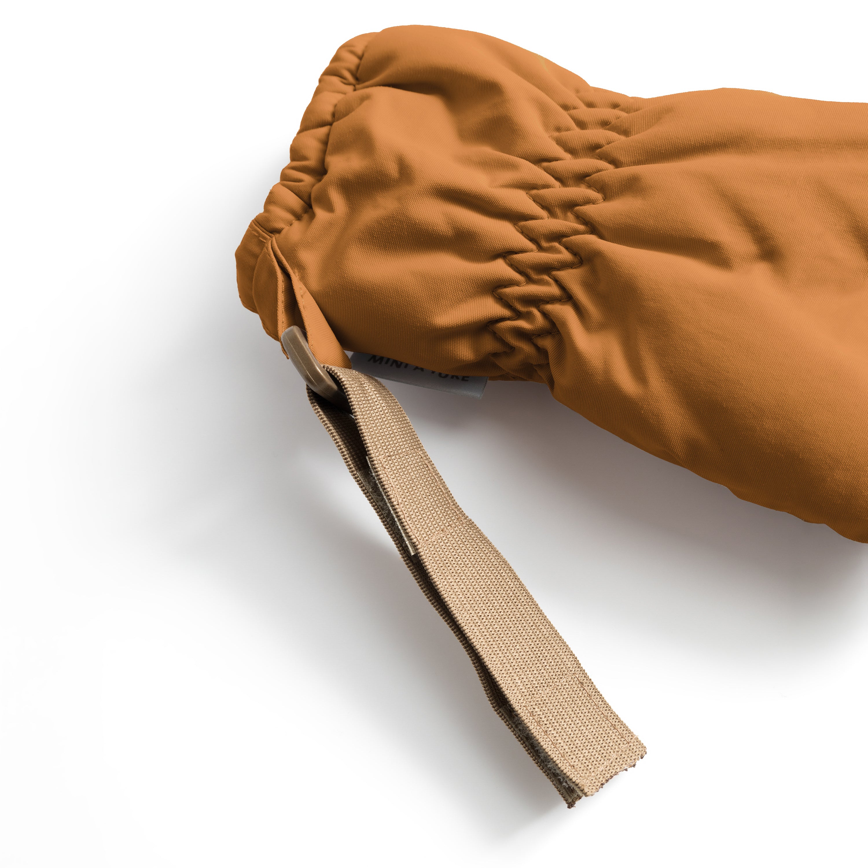 MATCORDT fleece lined mittens in caramel brown shown in close-up from the cuff, highlighting the elastic gathered wrist opening that seals out draughts and the extended beige velcro attachment strap designed to fasten to D-loops on MINI A TURE outerwear.