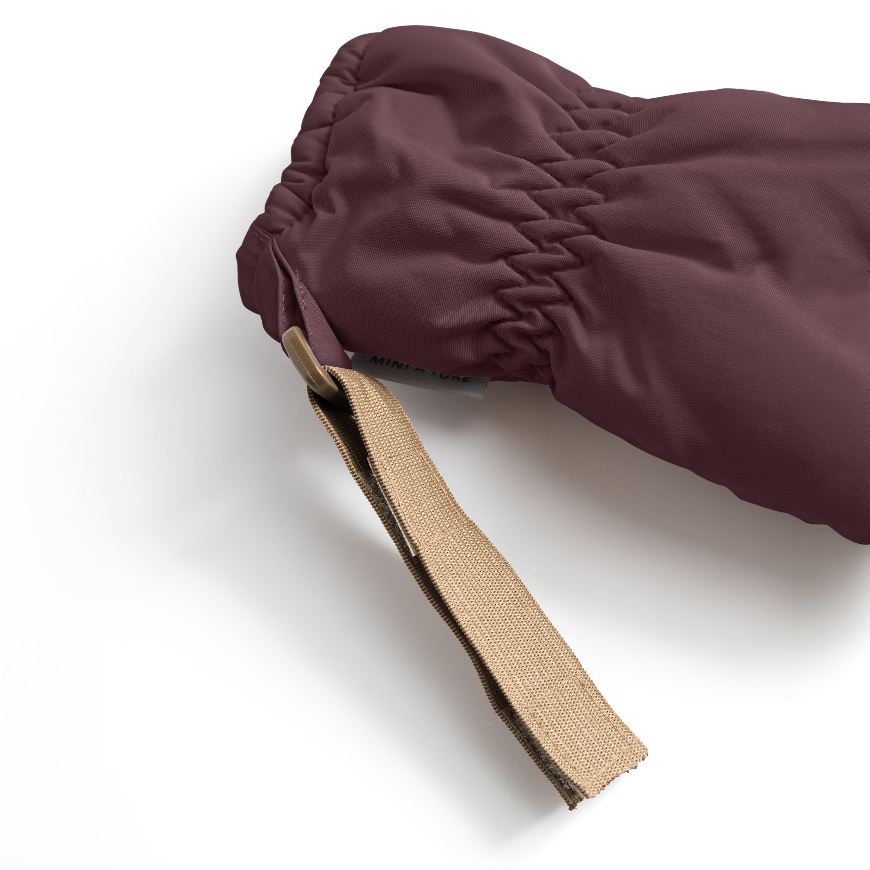 MATCORDT fleece lined mittens in deep plum shown in close-up from the cuff opening, highlighting the elastic gathered wrist construction and the extended beige velcro attachment strap with visible hook-and-loop fastening detail that secures to D-loops on MINI A TURE outerwear.