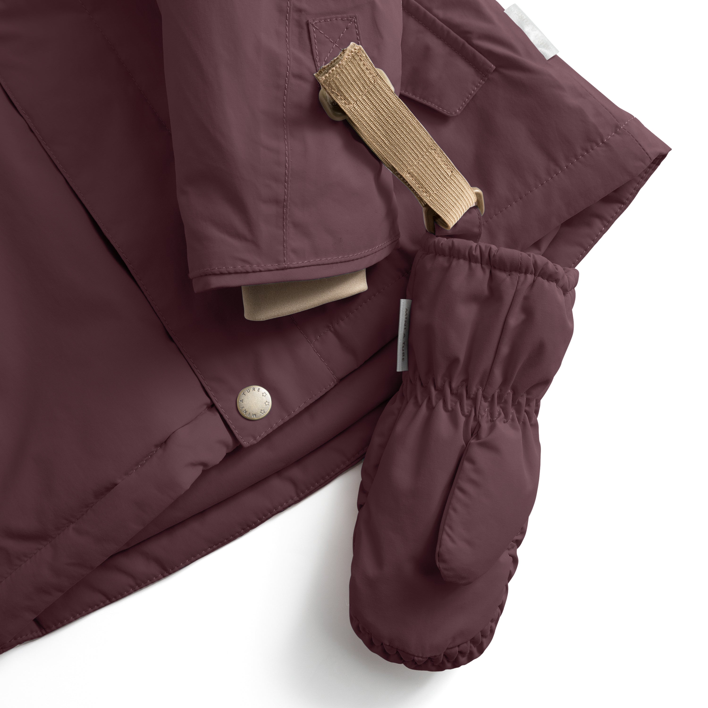 MATCORDT fleece lined mittens in deep plum shown attached to a matching jacket via the beige velcro strap and D-loop fastening, with the elastic gathered cuff and thumb visible alongside the jacket's press-stud closure and waterproof recycled polyamide construction.