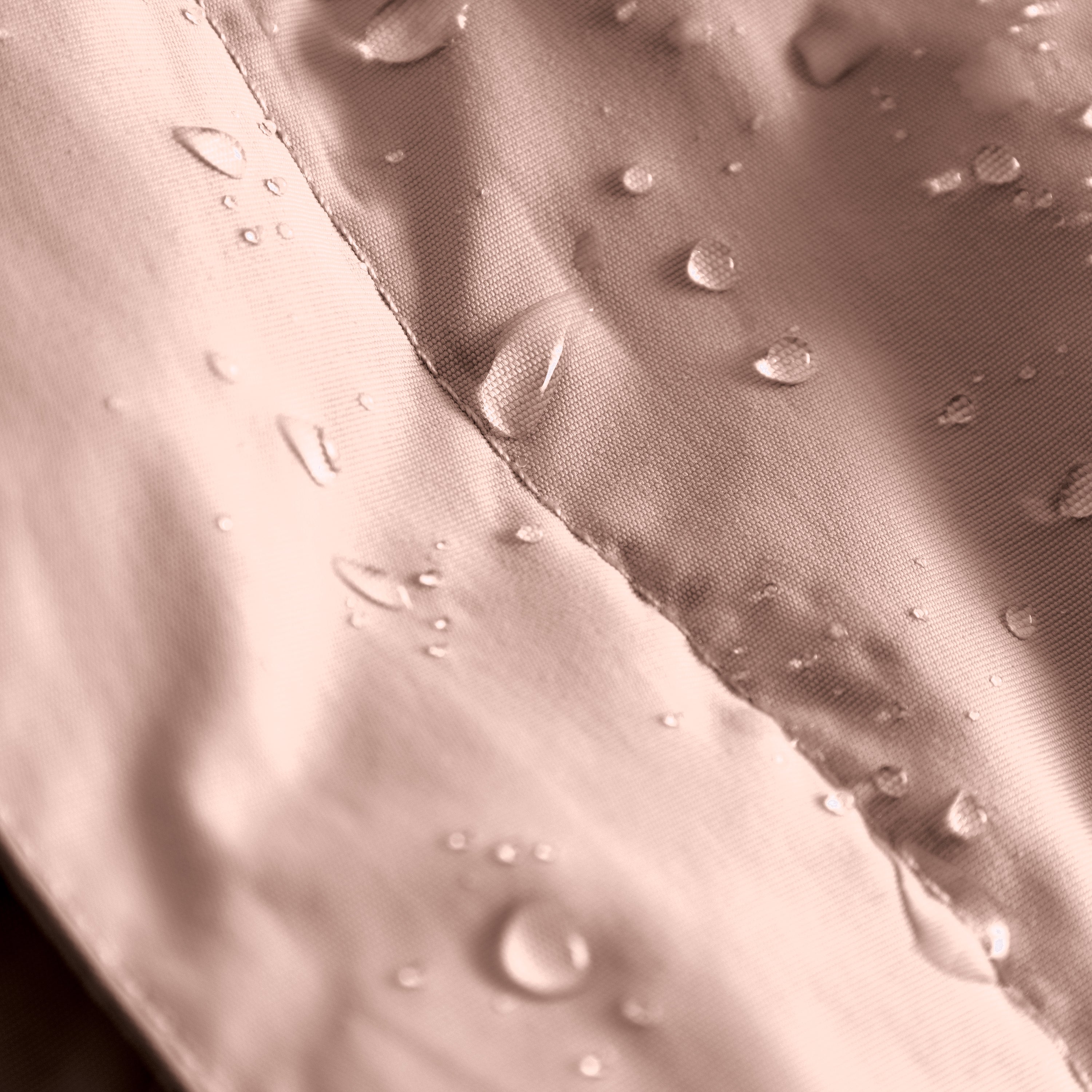MATBABYWEN anorak in soft pink showing water droplets beading on the fluorine-free Bionic Finish Eco treated recycled polyamide shell, with a close-up view of the fully taped seam construction demonstrating waterproof performance.
