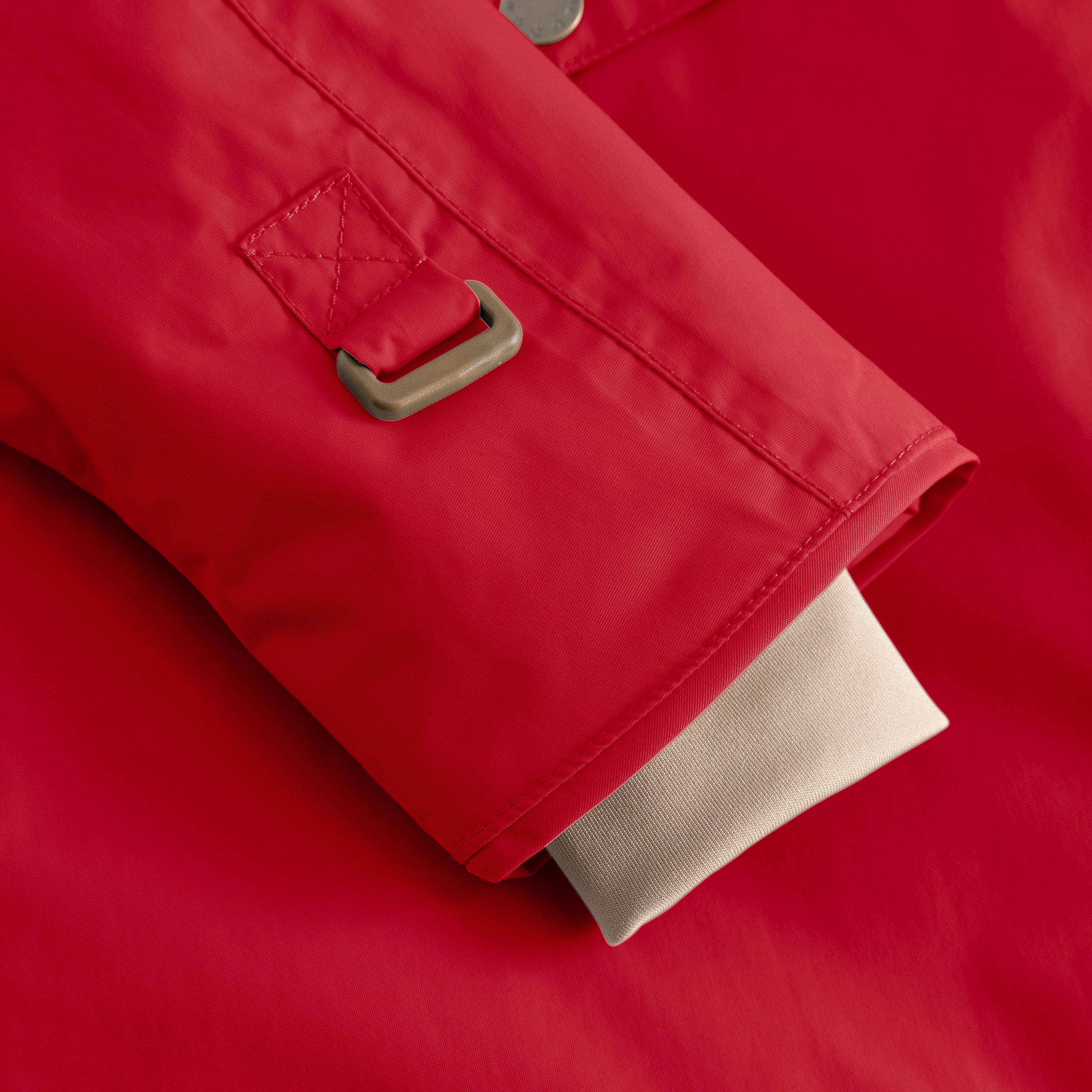 Detail of the MATWANG fleece-lined winter jacket's sleeve cuff showing the internal snow cuff with thumb opening and bronze-toned metal hook fastening, alongside the beige fleece lining visible at the hem of the red waterproof recycled nylon shell.