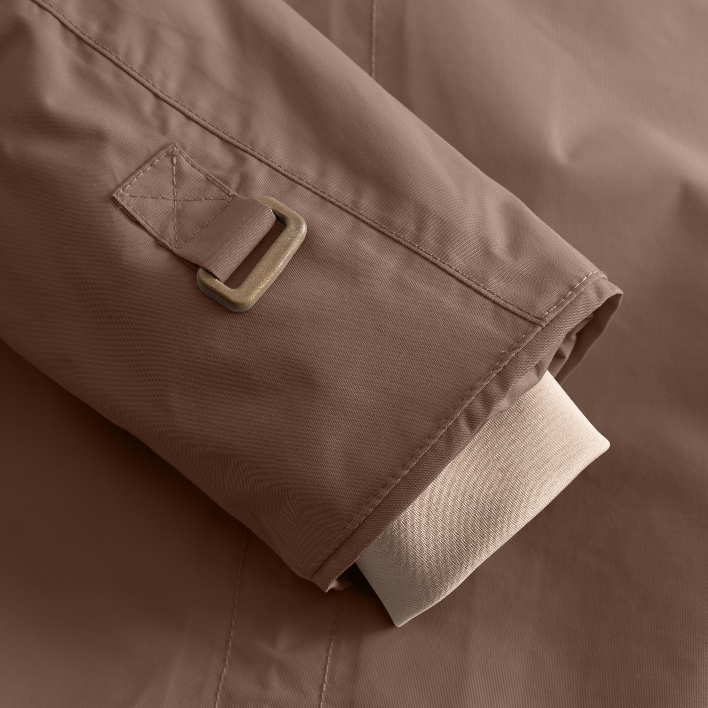 Detail of the MATWALLY fleece lined winter jacket sleeve in taupe, showing the adjustable snow cuff with metal D-ring and fabric tab, beige ribbed inner cuff extending below the outer sleeve and fully taped seam construction visible along the edge.