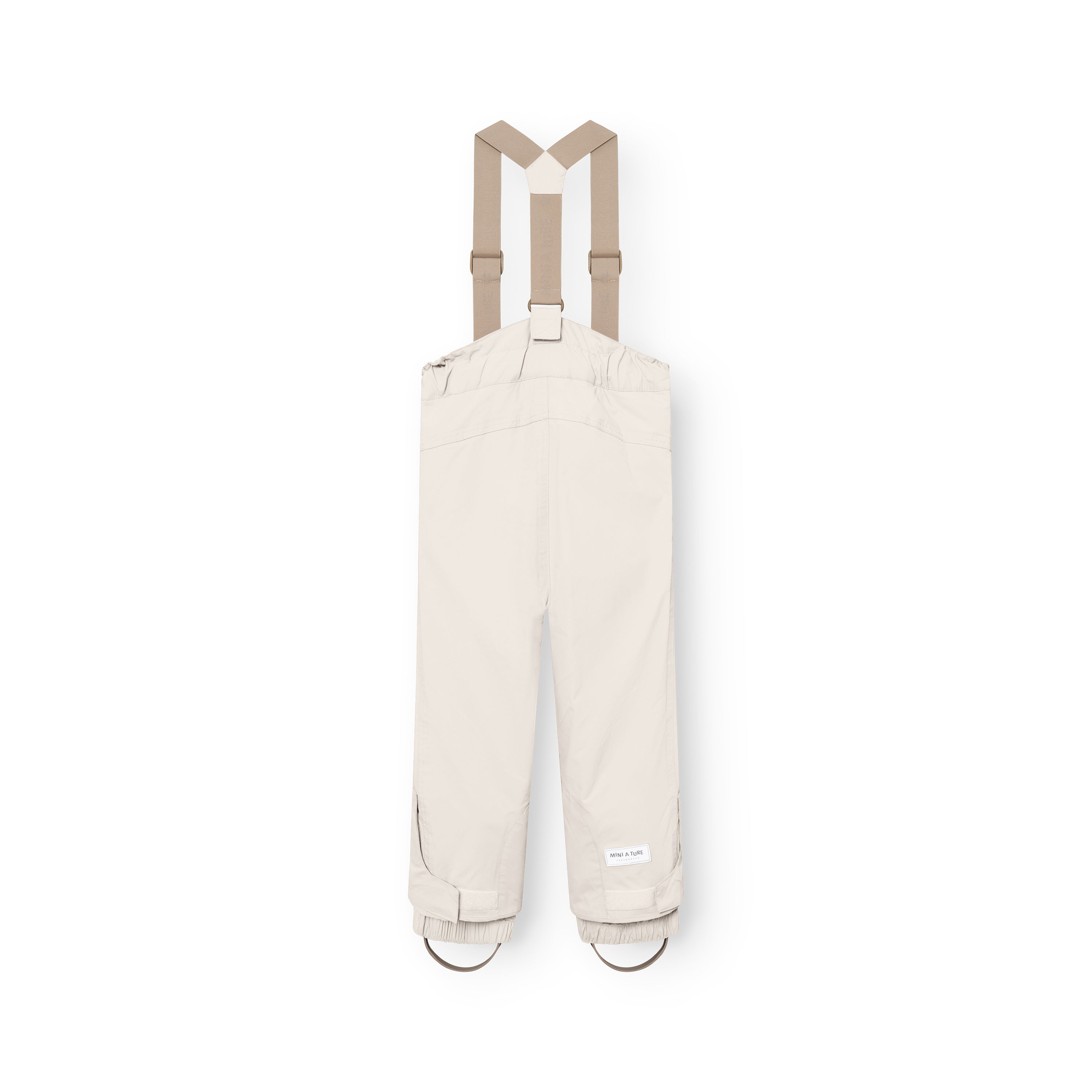 MATWITTE snow pants in cream viewed from the back, showing the cross-back elastic suspender attachment, elasticated ankle cuffs with integrated foot straps, and the MINI A TURE label positioned at the lower leg.