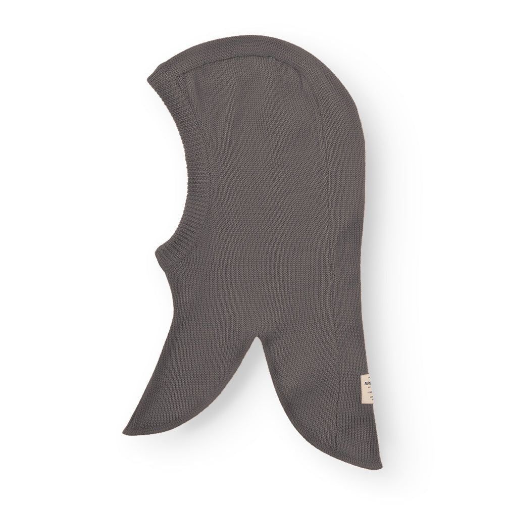 MATKEA light balaclava in charcoal grey merino wool, displayed flat to show the full-coverage silhouette with elongated side panels that protect the neck and shoulders, and a contoured face opening for breathable layering.