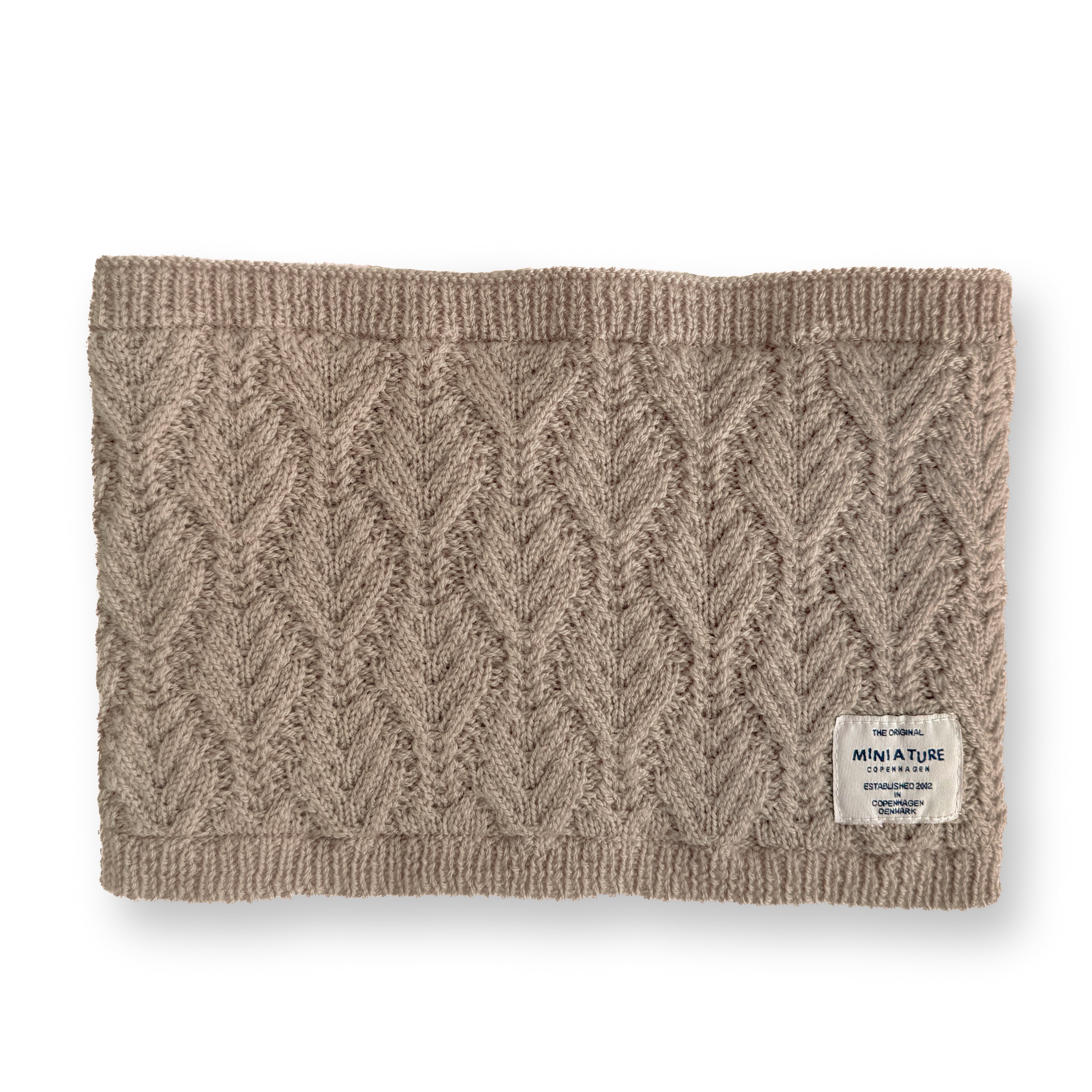 MATGOI fleece lined neckwarmer shown flat in warm beige merino wool with a chevron knit pattern, ribbed top and bottom edges, and a woven MINI A TURE label at the lower right.
