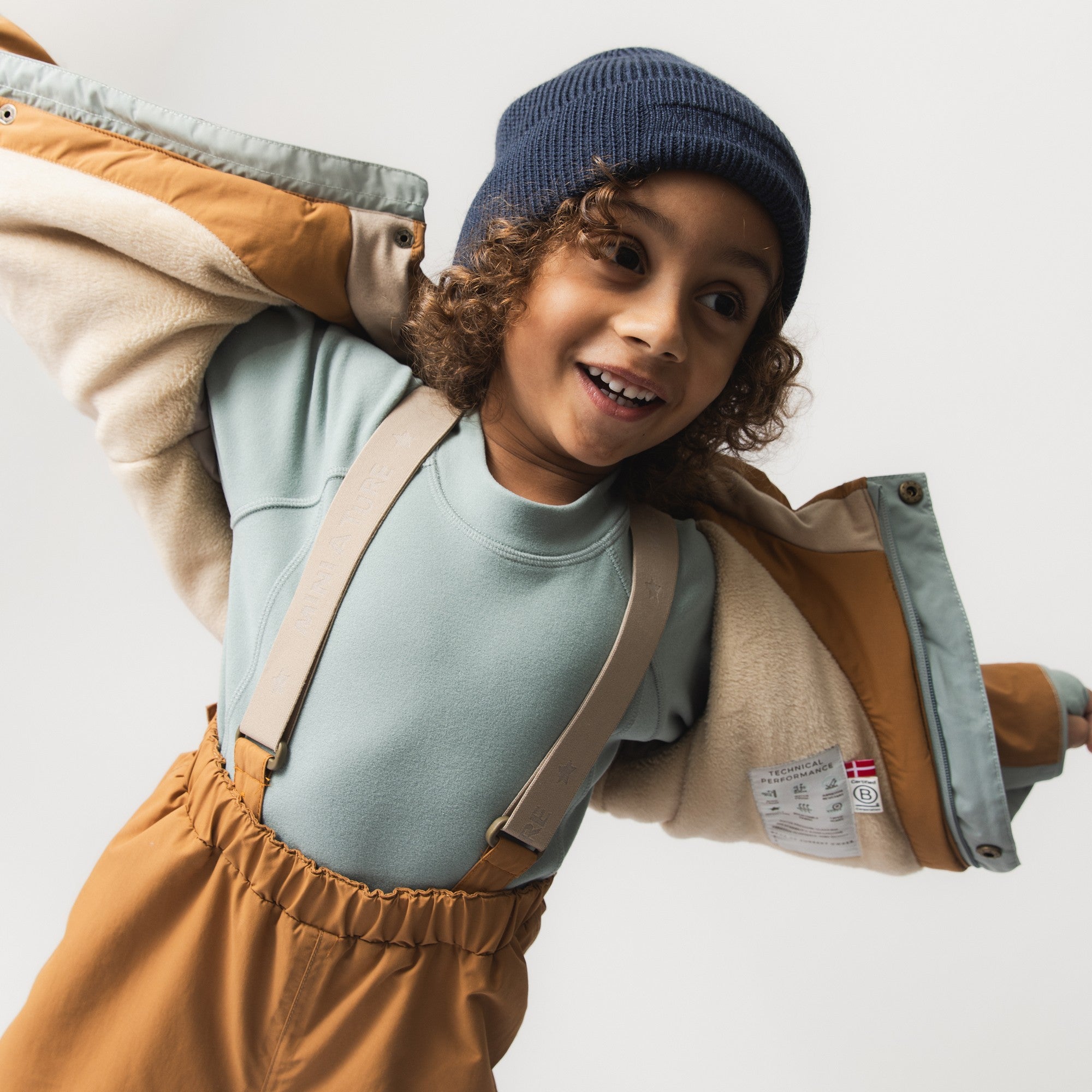 MATBOJE beanie in navy merino wool with a ribbed knit structure, worn by a smiling child in a fleece jacket and high-neck top.