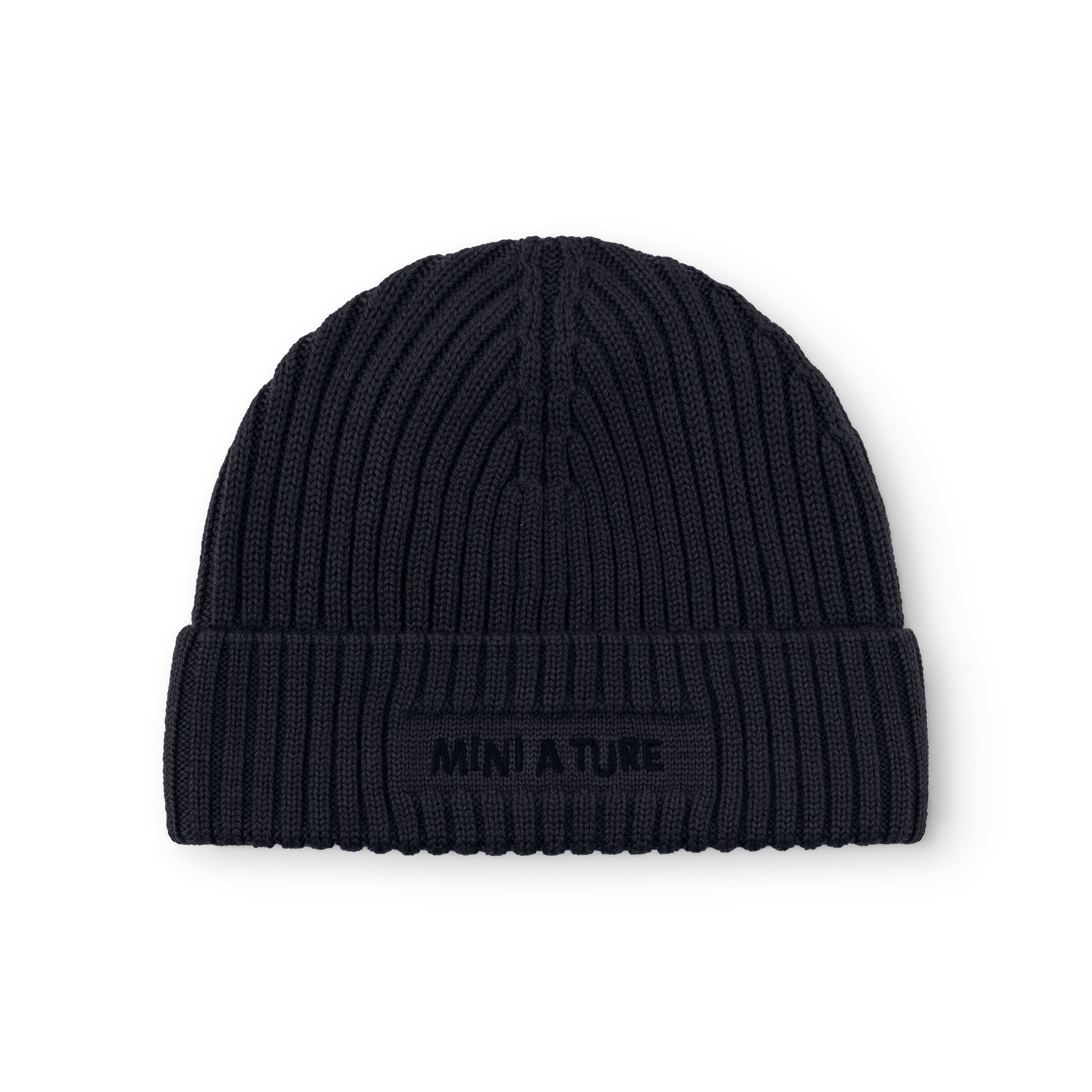 MATBOJE fleece lined beanie in navy merino wool with the fold-up brim worn in place, showing the tonal embroidered MINI A TURE logo and the vertical ribbed knit structure across the crown.
