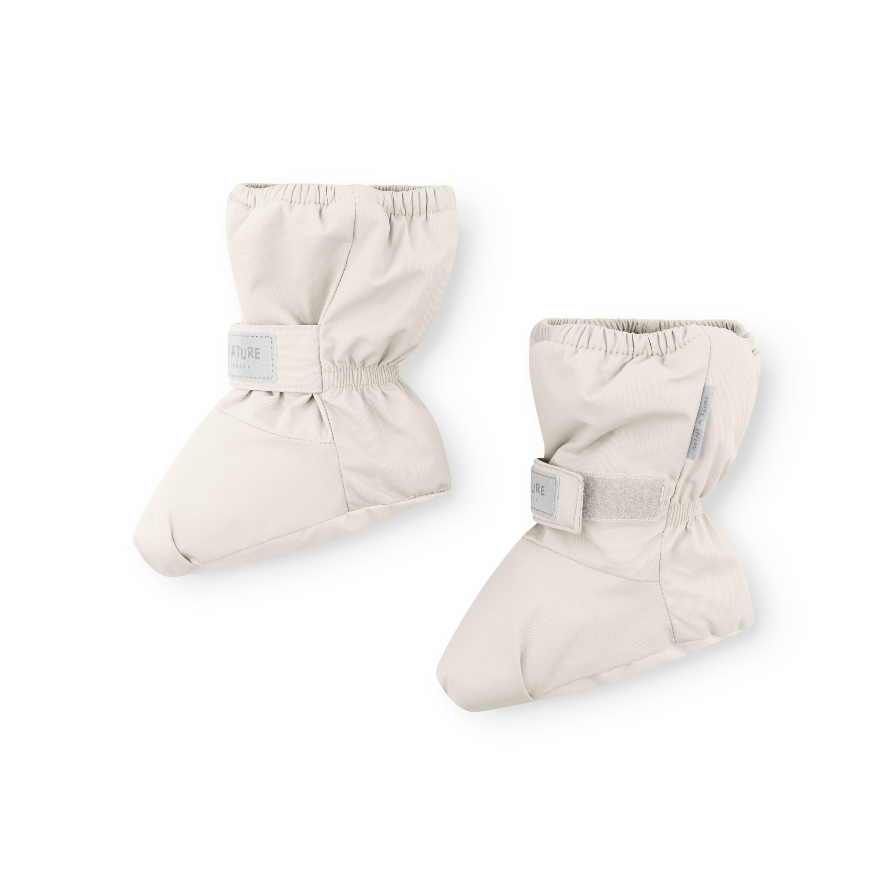 MATWINN waterproof baby outdoor socks in cream with adjustable velcro ankle strap and elasticated cuff, photographed as a pair against a white background to show the padded foot shape and taped seam construction for cold-weather pram use.