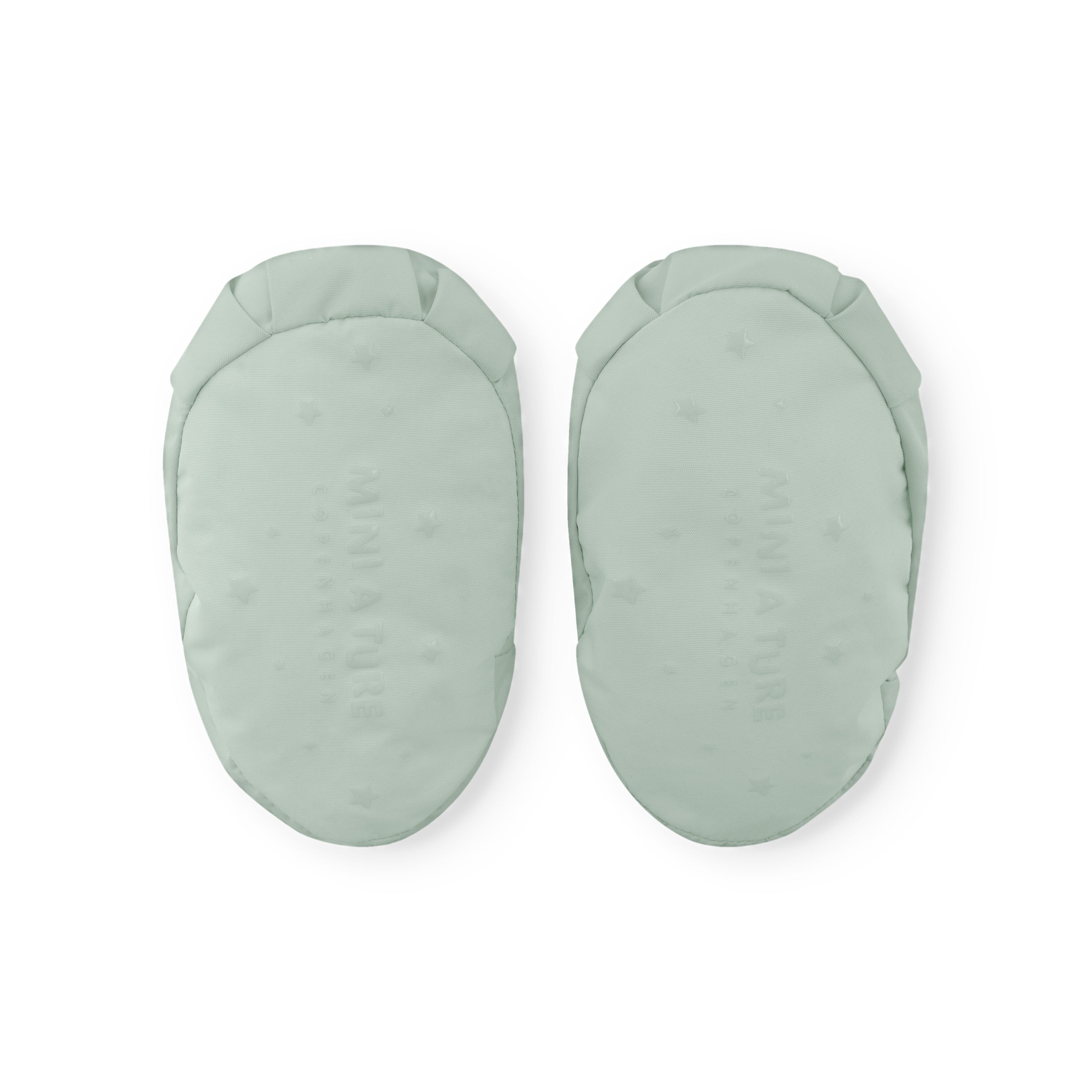 MATWINN fleece lined baby outdoor socks in pale mint green photographed as a pair from the sole, displaying the smooth waterproof recycled polyamide base with faint embossed logo and the padded oval shape designed for warmth during pram outings.