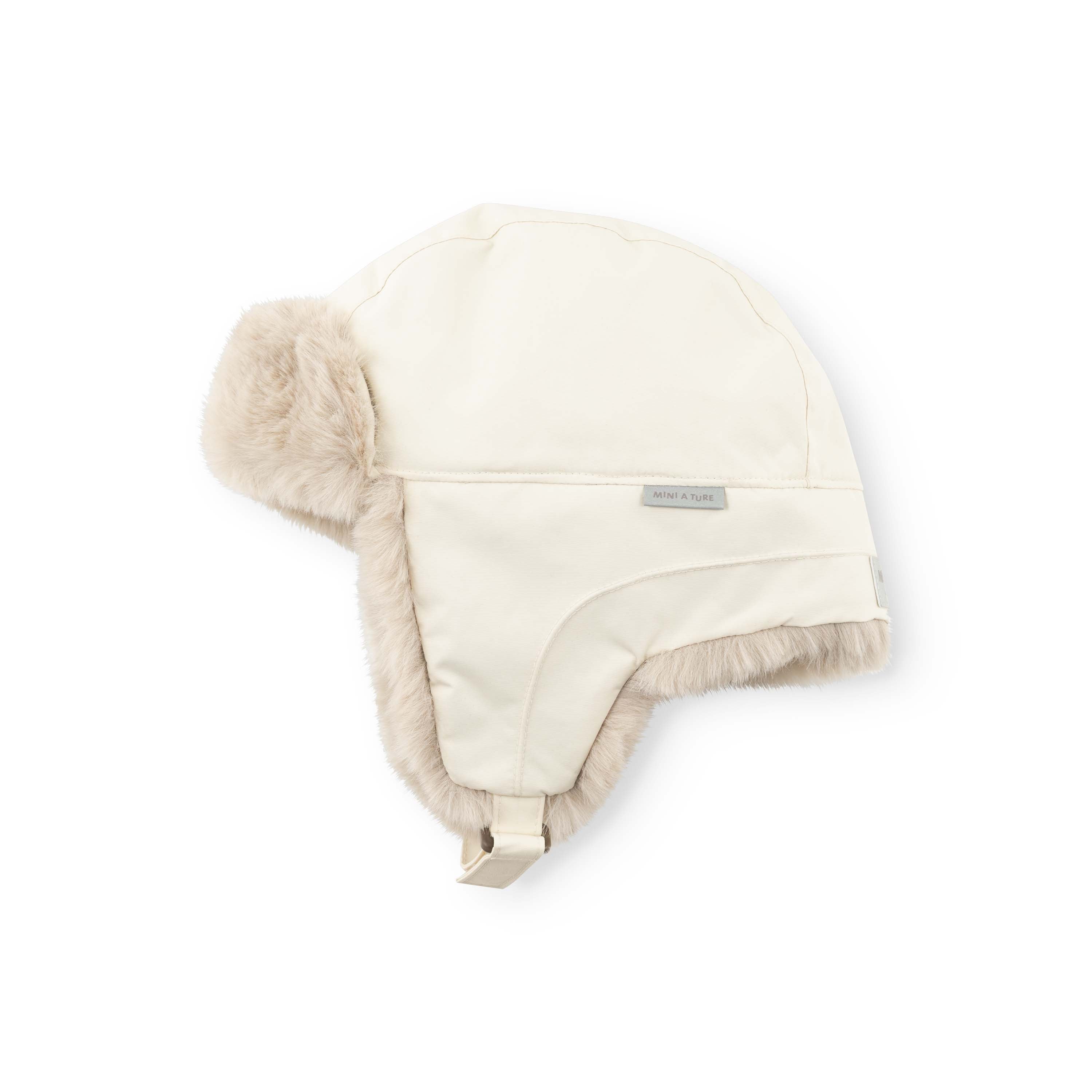 MATCRISTER waterproof children's trapper hat in off-white with soft beige fleece ear flaps and lining, laid flat showing the velcro chin strap and MINI A TURE label.