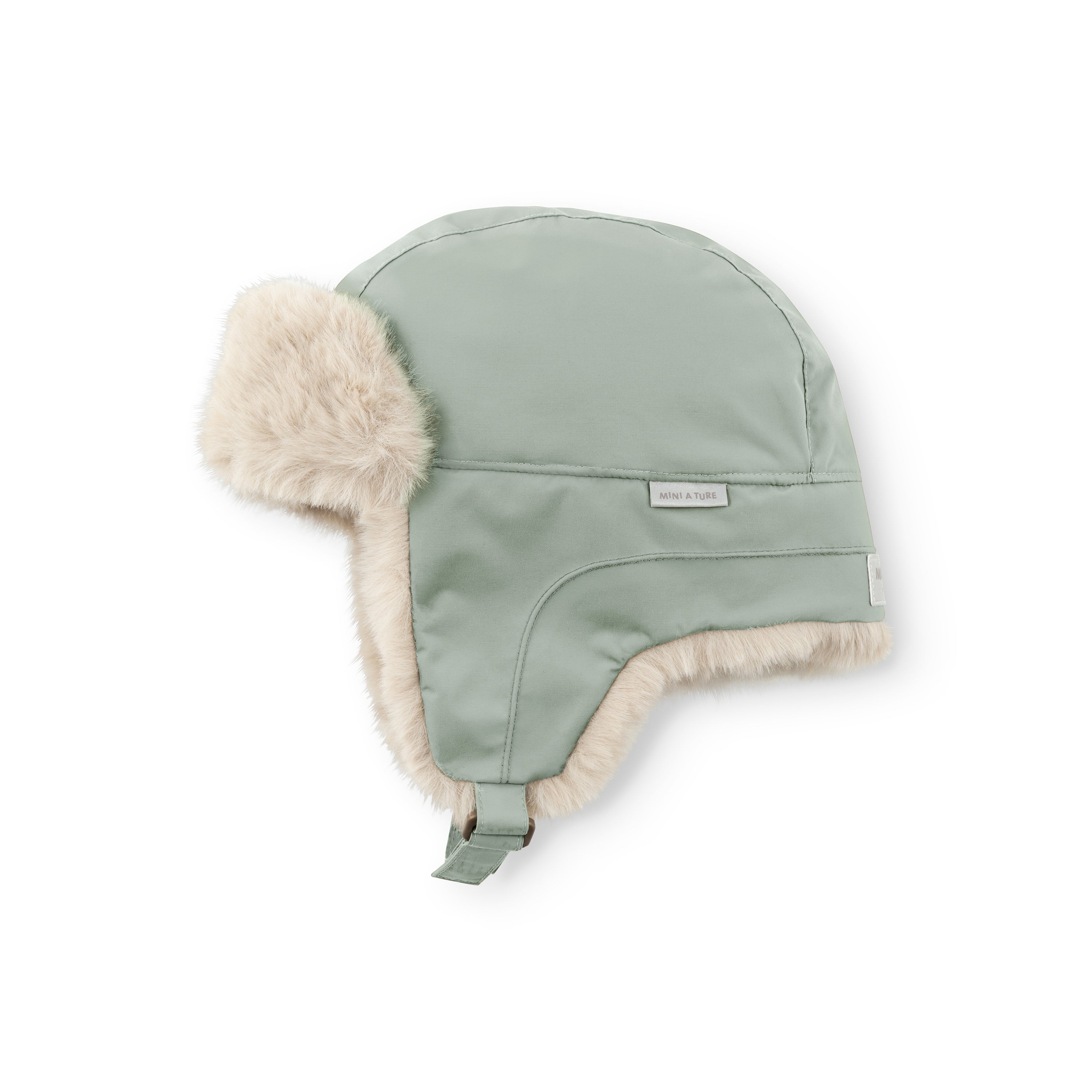 MATCRISTER children's winter hood in muted sage green with pale beige fleece ear flaps and lining, displayed at an angle showing the waterproof recycled nylon crown, velcro chin strap and MINI A TURE woven label.