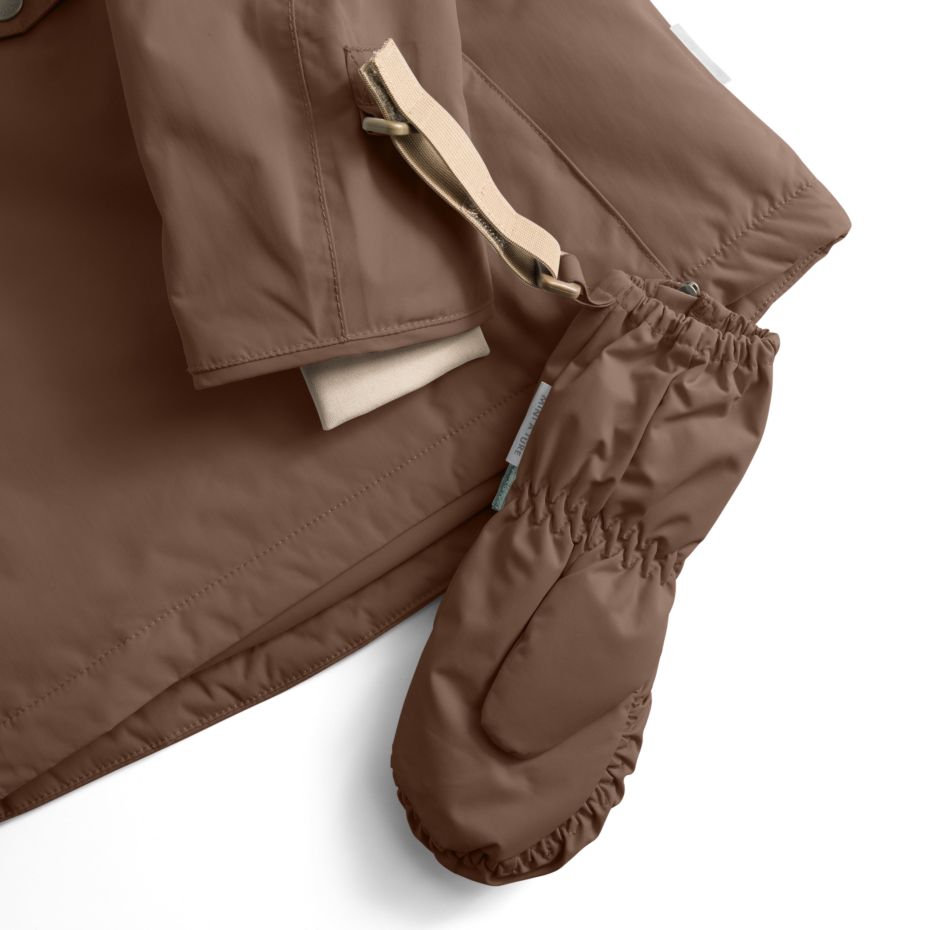 MATCESAR mitten in warm brown shown with the full-length front zip open to reveal the soft fleece lining, elastic gathered cuff and beige webbing strap with metal D-ring, positioned beside matching waterproof trousers to demonstrate coordinated winter outerwear.