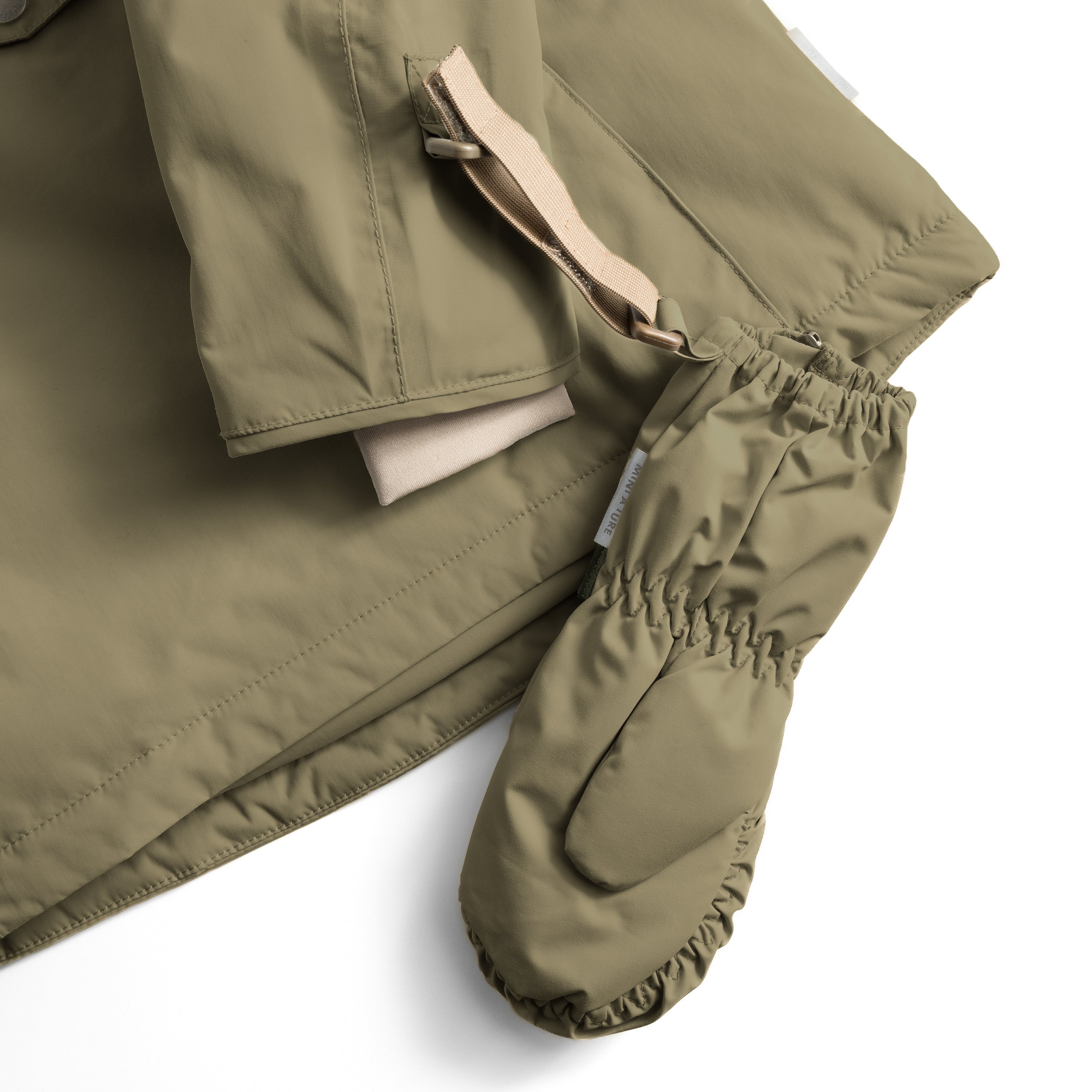Close-up of MATCESAR mitten in olive green showing the elastic gathered cuff with MINI A TURE branding, beige webbing strap with velcro fastening, and the soft fleece lining visible inside the cuff opening.