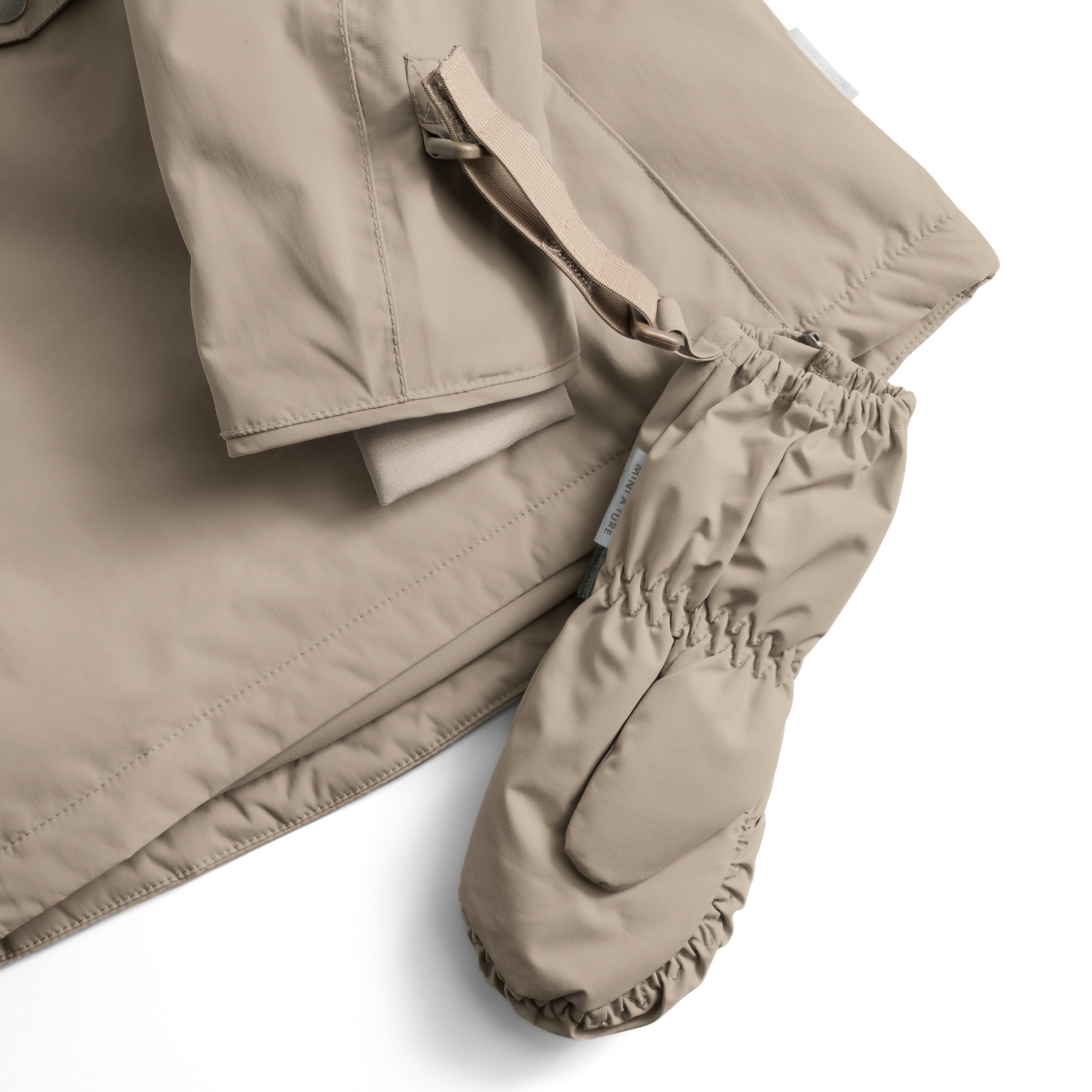MATCESAR waterproof mittens in beige taupe shown flat with elastic gathered cuffs, beige webbing strap with D-ring attachment and full-length front zip visible, highlighting the recycled polyamide shell and MINI A TURE branded elastic detailing.