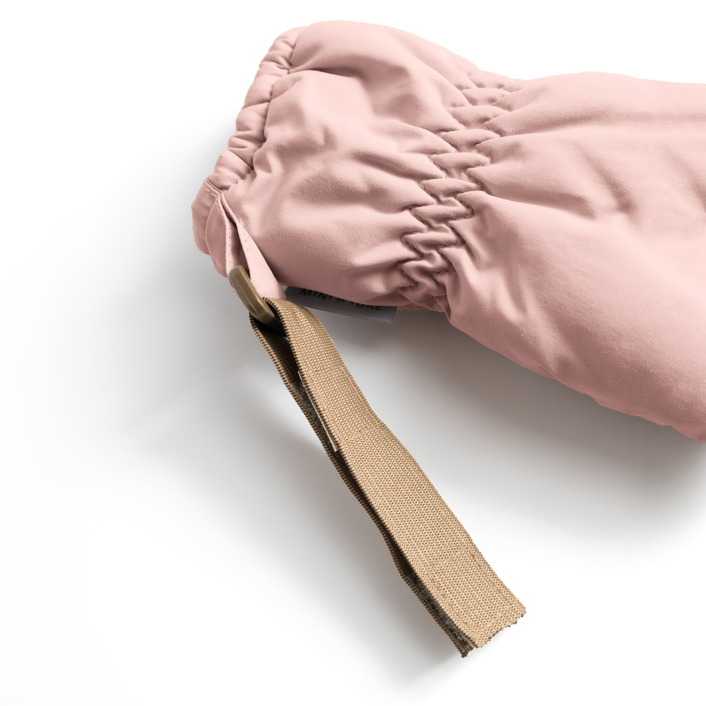 MATCORDT fleece lined mittens in pale pink shown in close-up from the cuff, highlighting the elastic gathered wrist opening and the extended beige velcro attachment strap designed to fasten to D-loops on MINI A TURE outerwear.