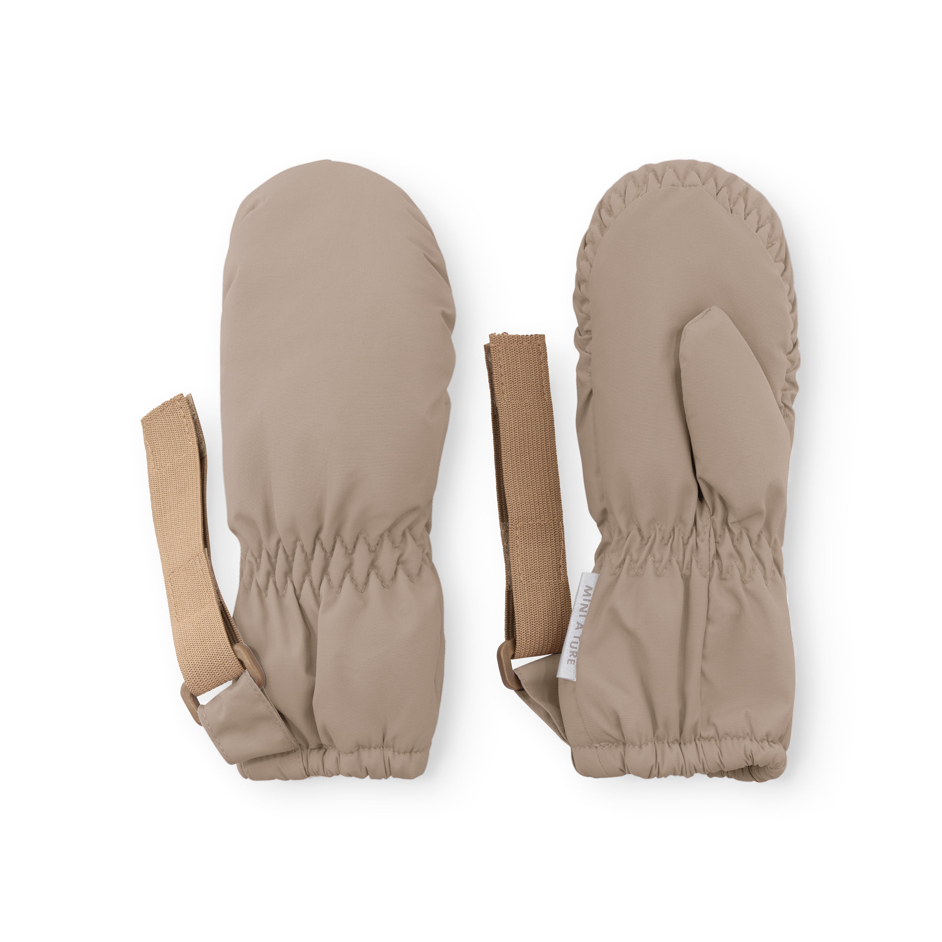 MATCORDT fleece lined mittens in pale cream displayed flat on a white background, showing the waterproof outer shell, palm side with elastic gathered cuffs at wrist and top, extended beige velcro attachment straps and a visible MINI A TURE care label.