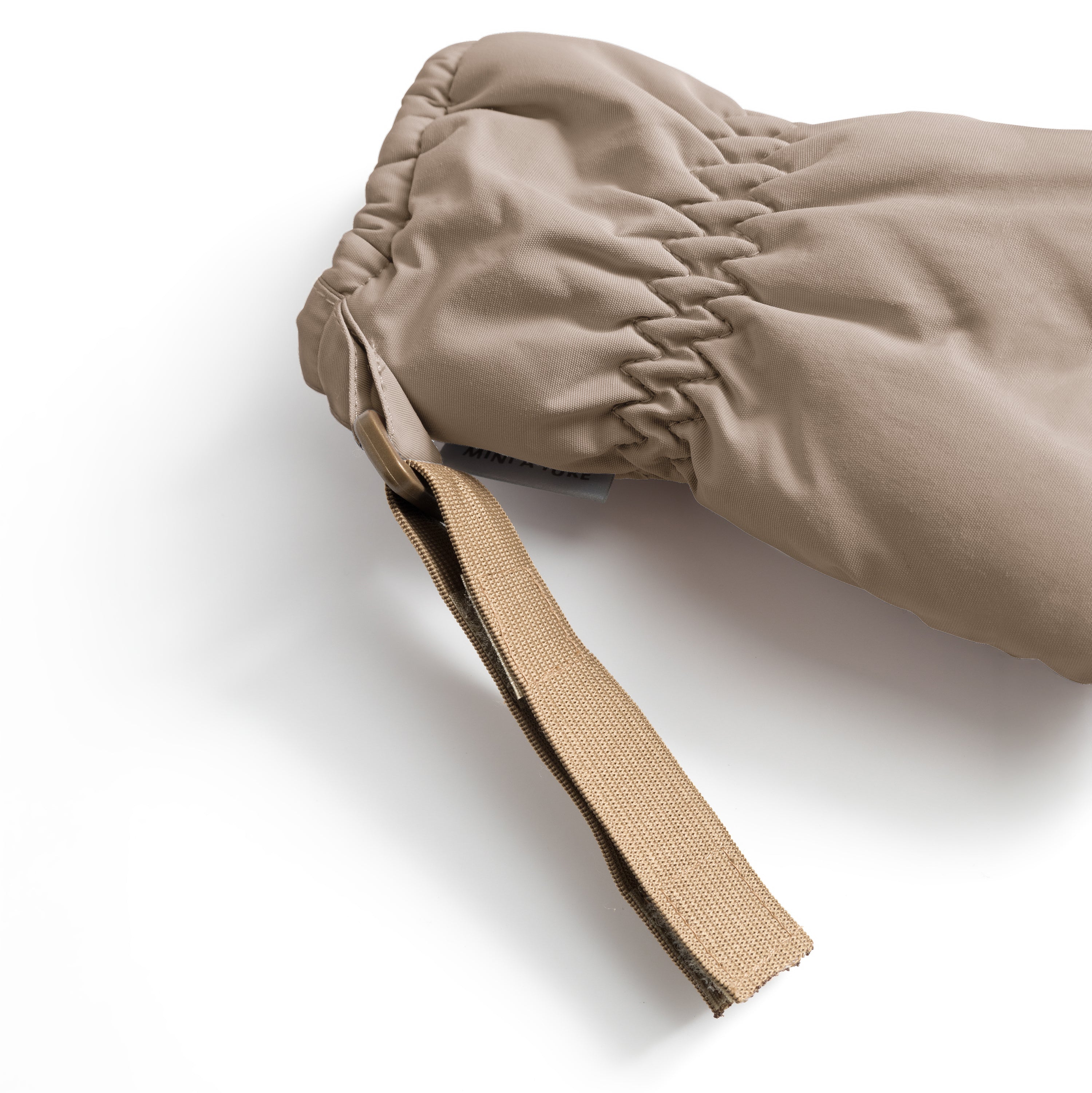 MATCORDT fleece lined mittens in pale cream shown in close-up at the cuff opening, with the elastic gathered construction visible creating a secure seal, the beige velcro attachment strap extending outward and the waterproof recycled polyamide shell displaying subtle texture and stitching detail.
