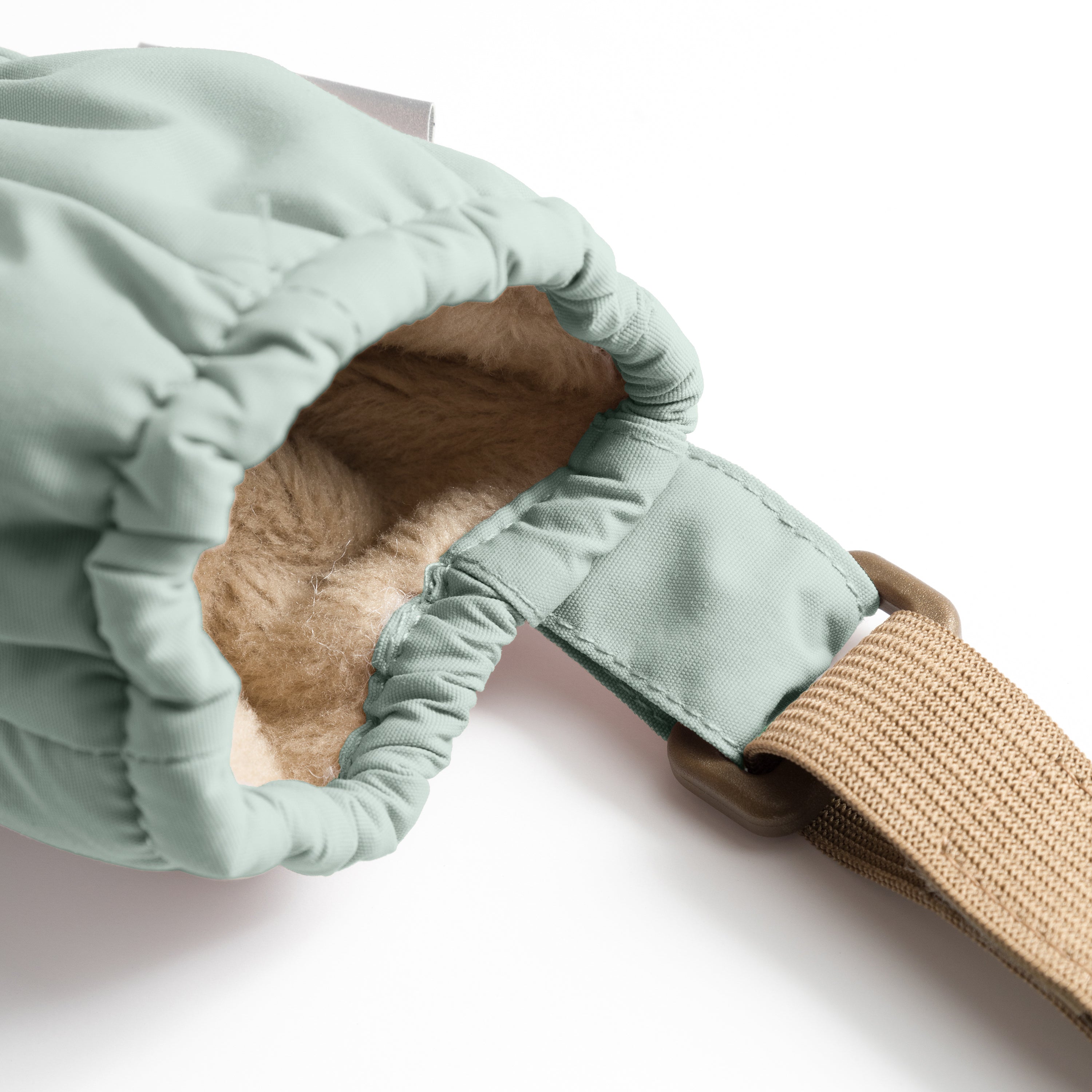 MATCORDT fleece lined mittens in pale mint green shown worn on a hand, with the elastic gathered cuff sealing closely around the wrist, the beige fleece lining visible at the opening and the extended beige velcro attachment strap positioned alongside the waterproof recycled polyamide shell.