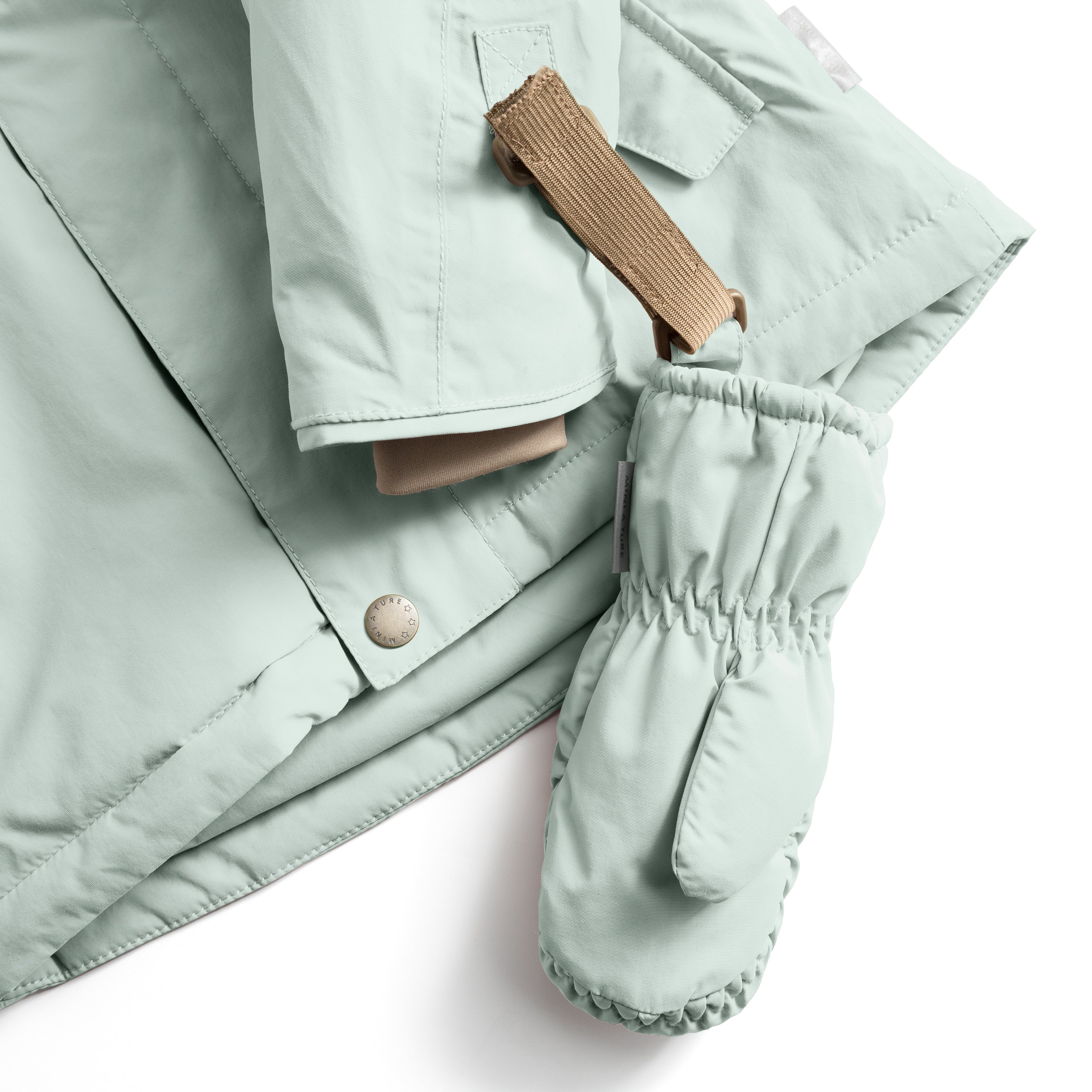 MATCORDT fleece lined mittens in pale mint green shown attached to a matching jacket sleeve, with the beige velcro strap threaded through the D-loop fastening, the elastic gathered cuff sealing the wrist and the waterproof recycled polyamide shell visible alongside the jacket's press-stud closure and taped seams.