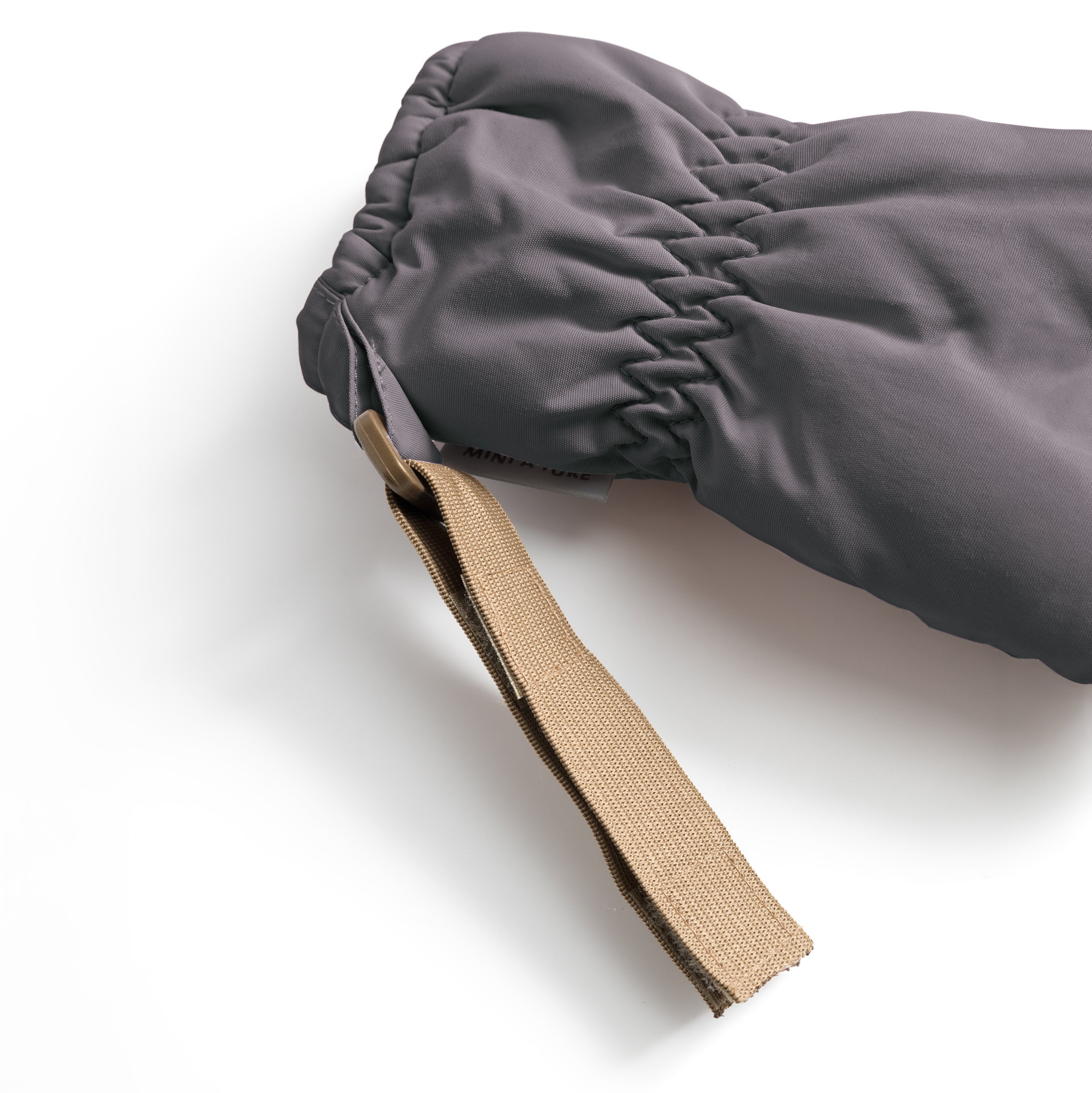 MATCORDT fleece lined mittens in grey shown in close-up from the cuff, revealing the elastic gathered opening that seals out cold air, the soft fleece lining visible at the interior edge and the extended beige velcro attachment strap.