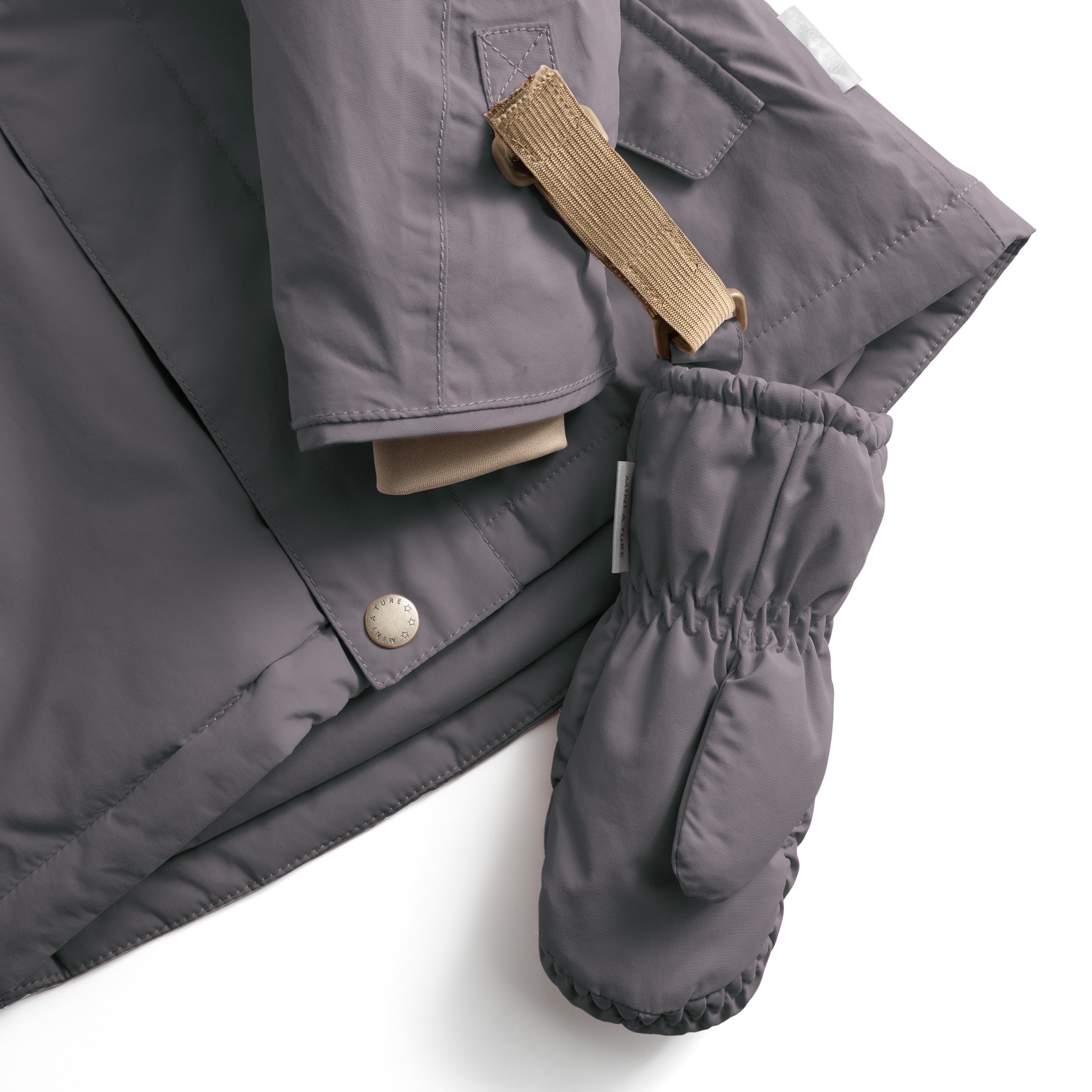 MATCORDT fleece lined mittens in grey shown attached to a matching jacket via the beige velcro strap threaded through a D-loop, demonstrating the secure fastening system that prevents gloves being lost during journeys and transitions.
