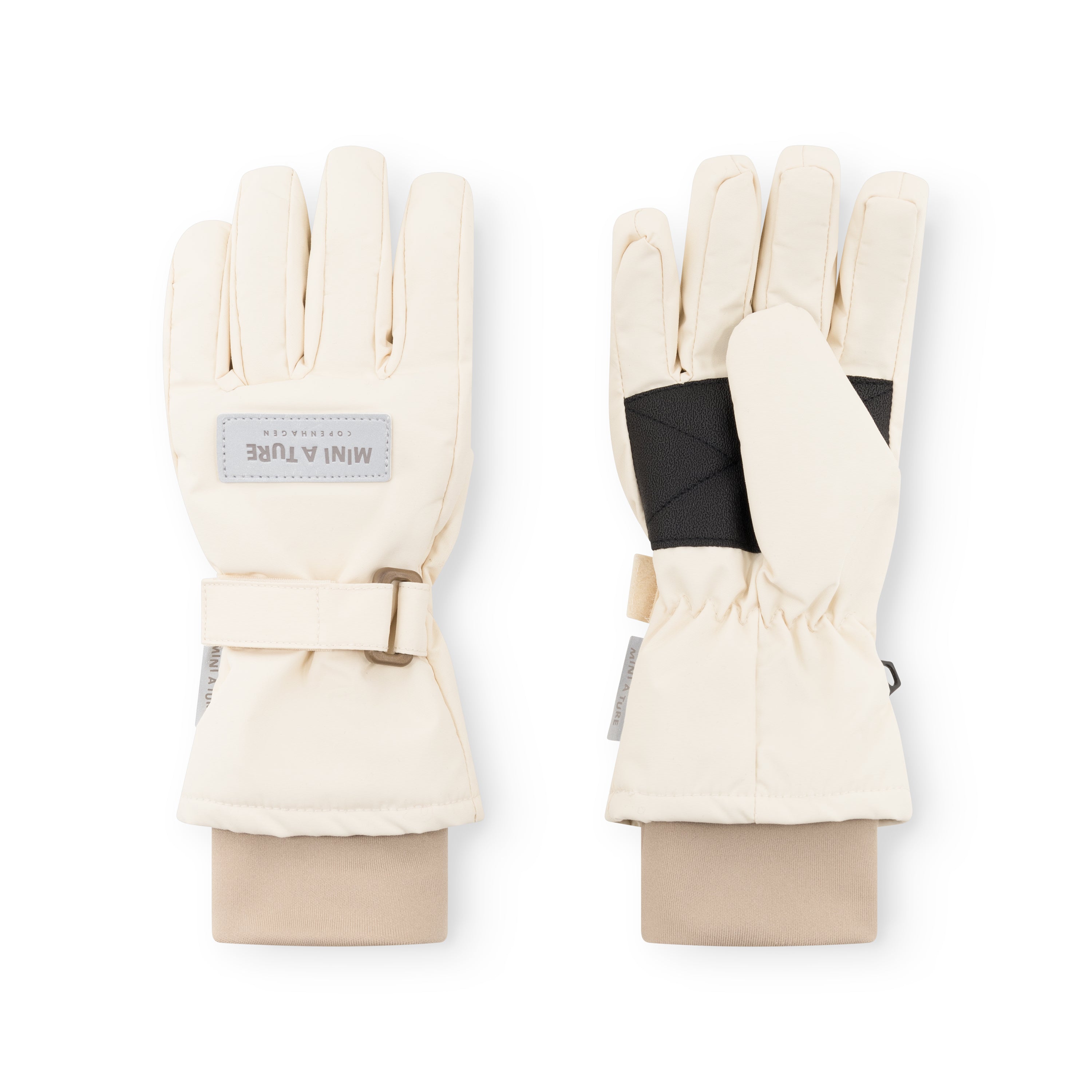 MATCELIO gloves in cream showing palm and back views, with MINI A TURE Copenhagen label on the back of hand, black elasticated internal wrist cuff visible, and adjustable buckle strap on the extended cuff.