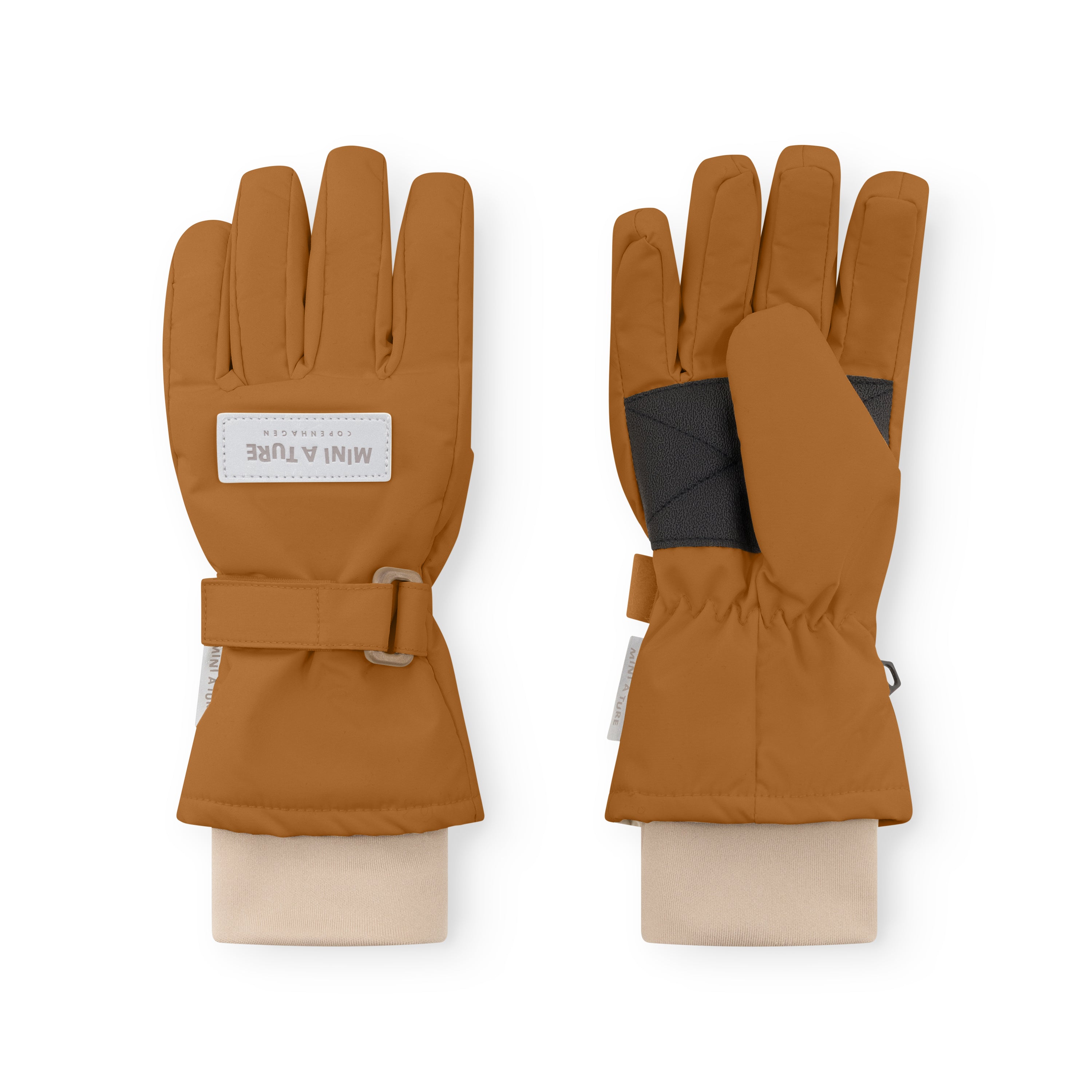MATCELIO gloves in caramel brown showing both palm and back, with MINI A TURE Copenhagen label on the back of hand, black elasticated wrist cuff and buckle strap closure visible on extended cuff.