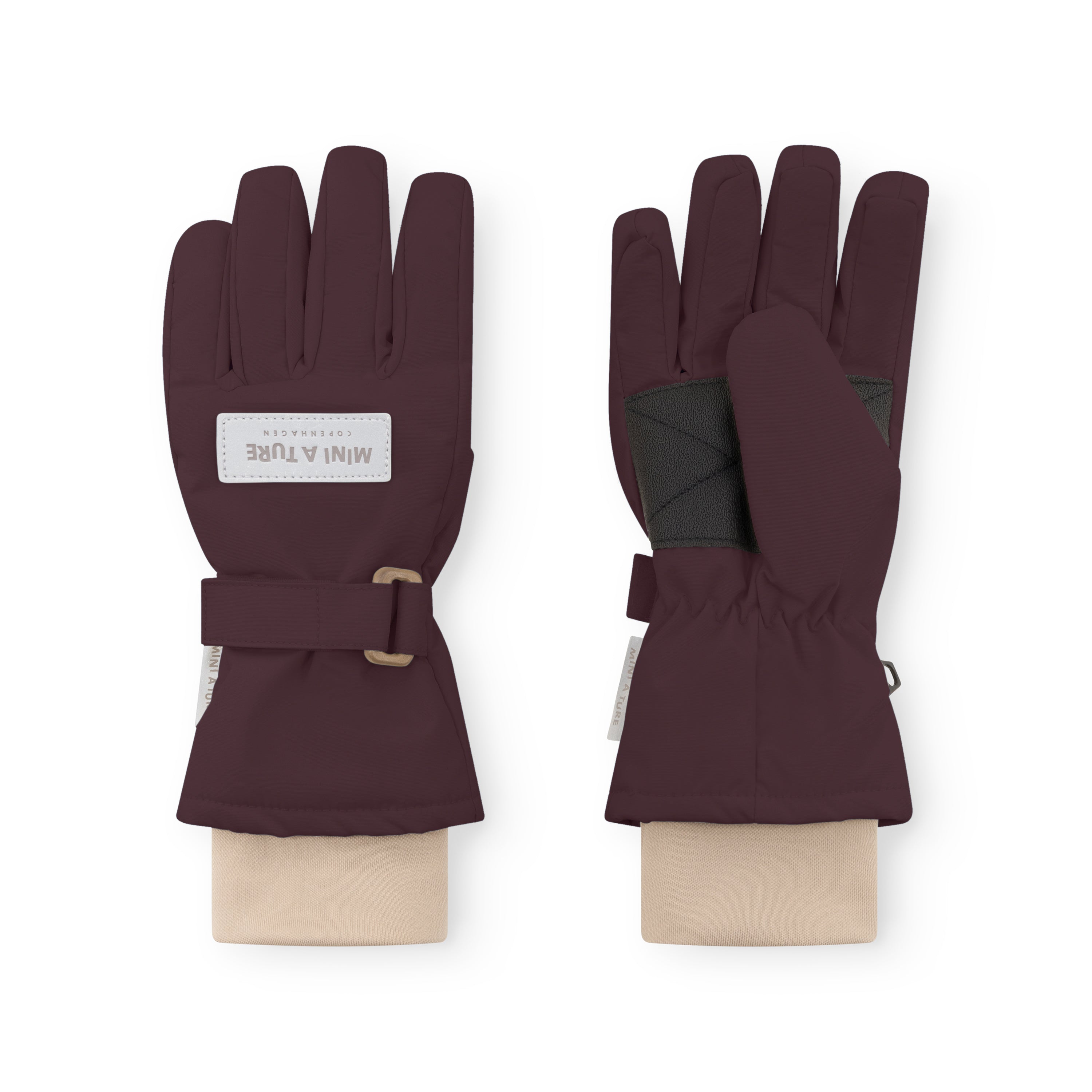MATCELIO gloves in deep burgundy showing palm and back views, with MINI A TURE Copenhagen label on the back of hand, black elasticated internal wrist cuff visible, and adjustable buckle strap on the extended cuff.