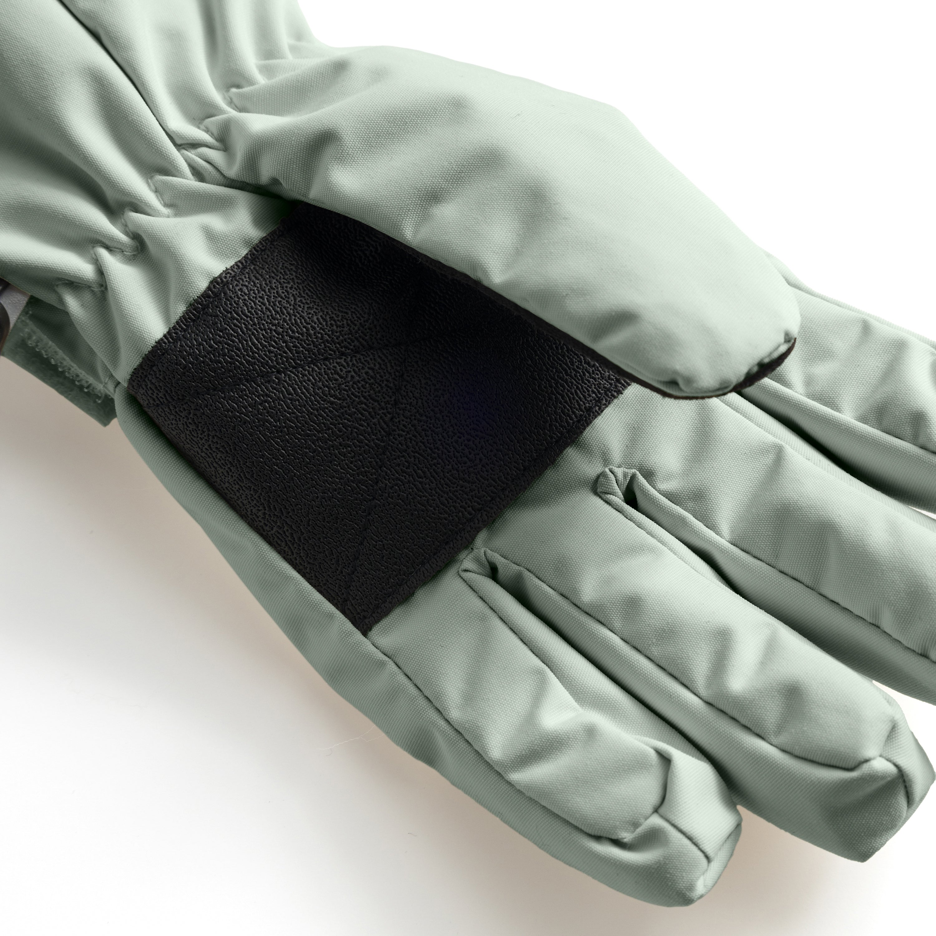 MATCELIO gloves in soft sage green photographed in close-up to show the black elasticated wrist cuff positioned inside the extended sage cuff, demonstrating the dual-layer construction that seals out cold air and snow during winter wear.