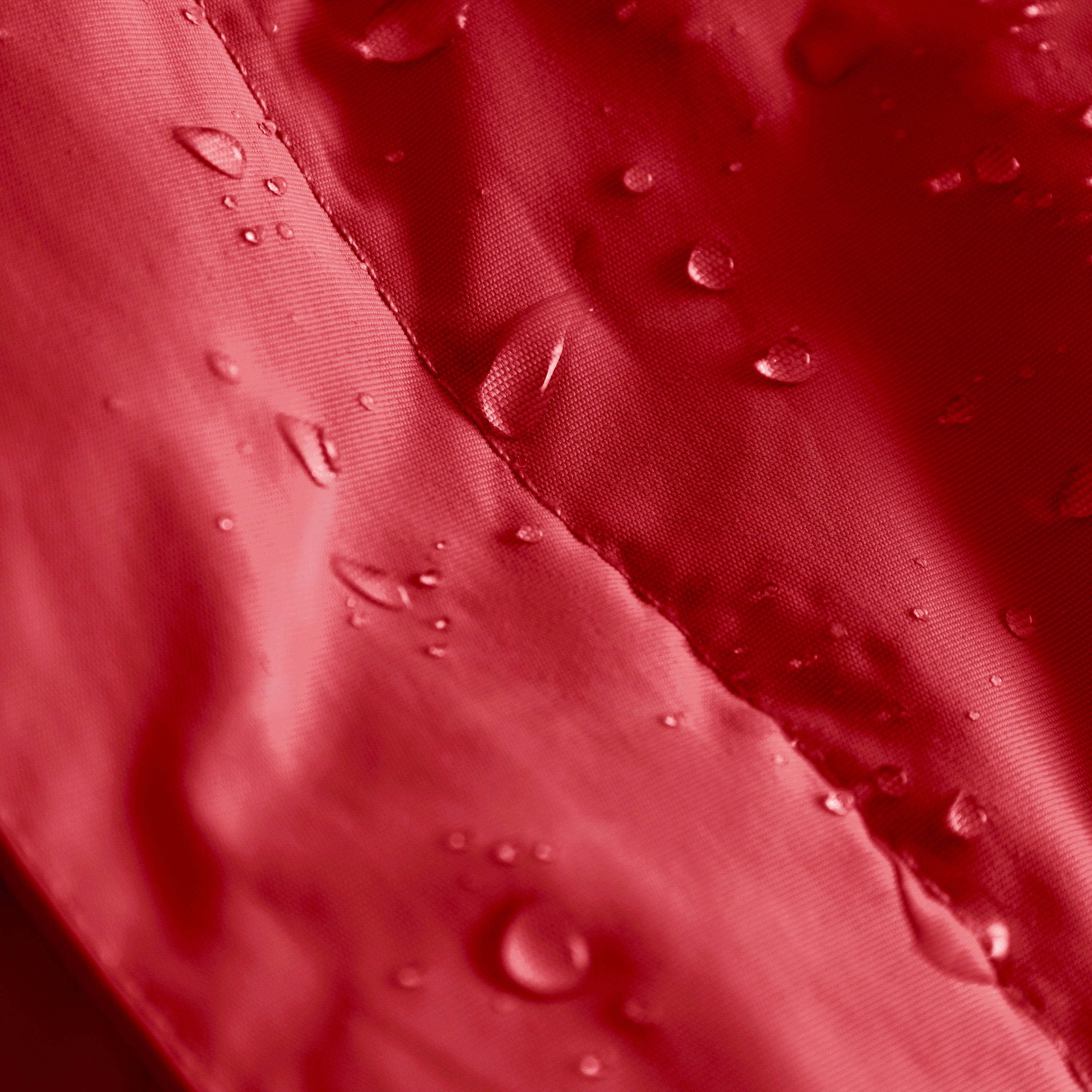 Close-up of the MATBABYWEN anorak in red showing water droplets beading on the recycled polyamide outer shell treated with fluorine-free Bionic Finish Eco, with a detailed view of the taped seam running diagonally across the waterproof fabric.