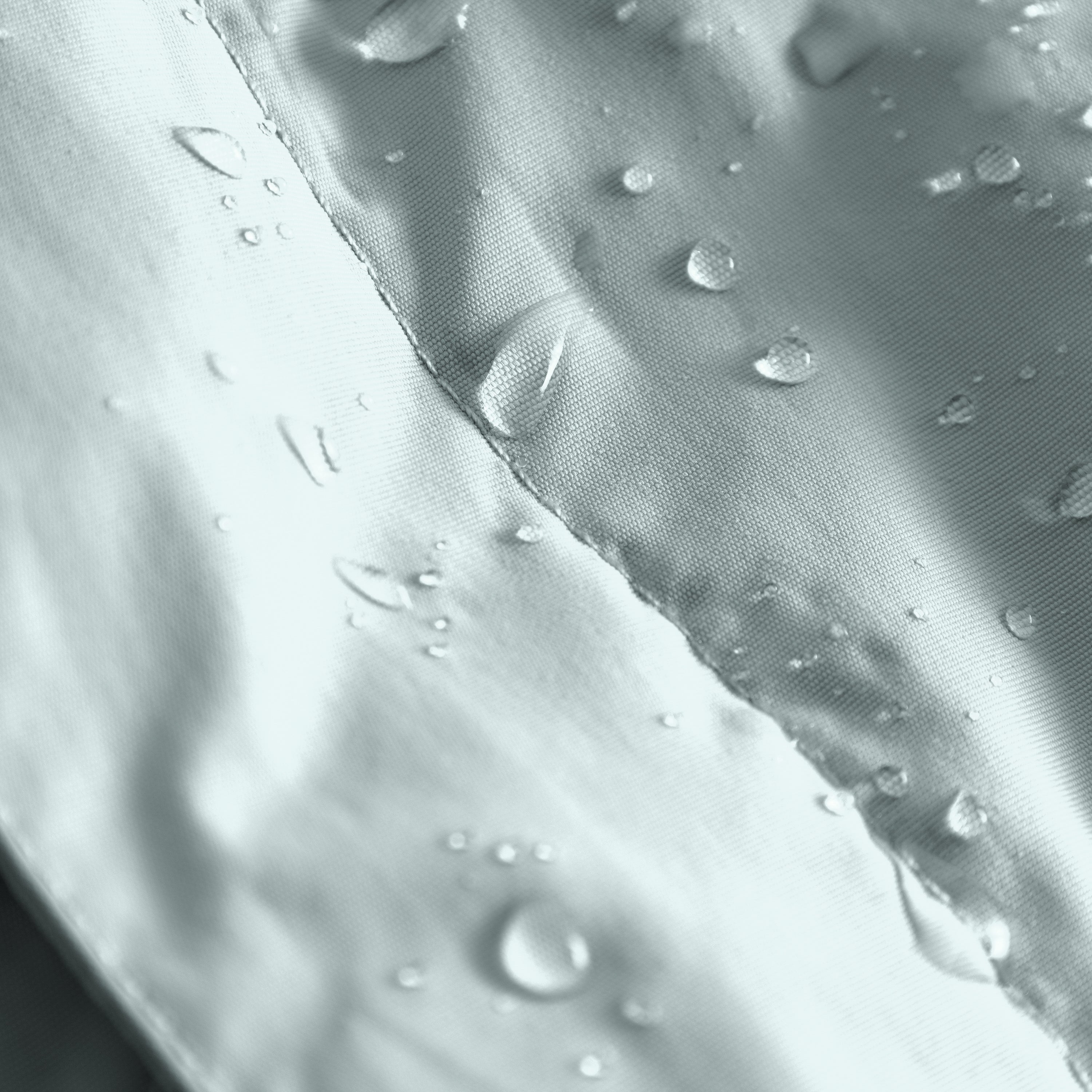 MATBABYWEN anorak in pale blue-grey showing water droplets beading on the fluorine-free Bionic Finish Eco treated recycled polyamide shell, with a detailed view of the fully taped seam construction demonstrating waterproof performance.