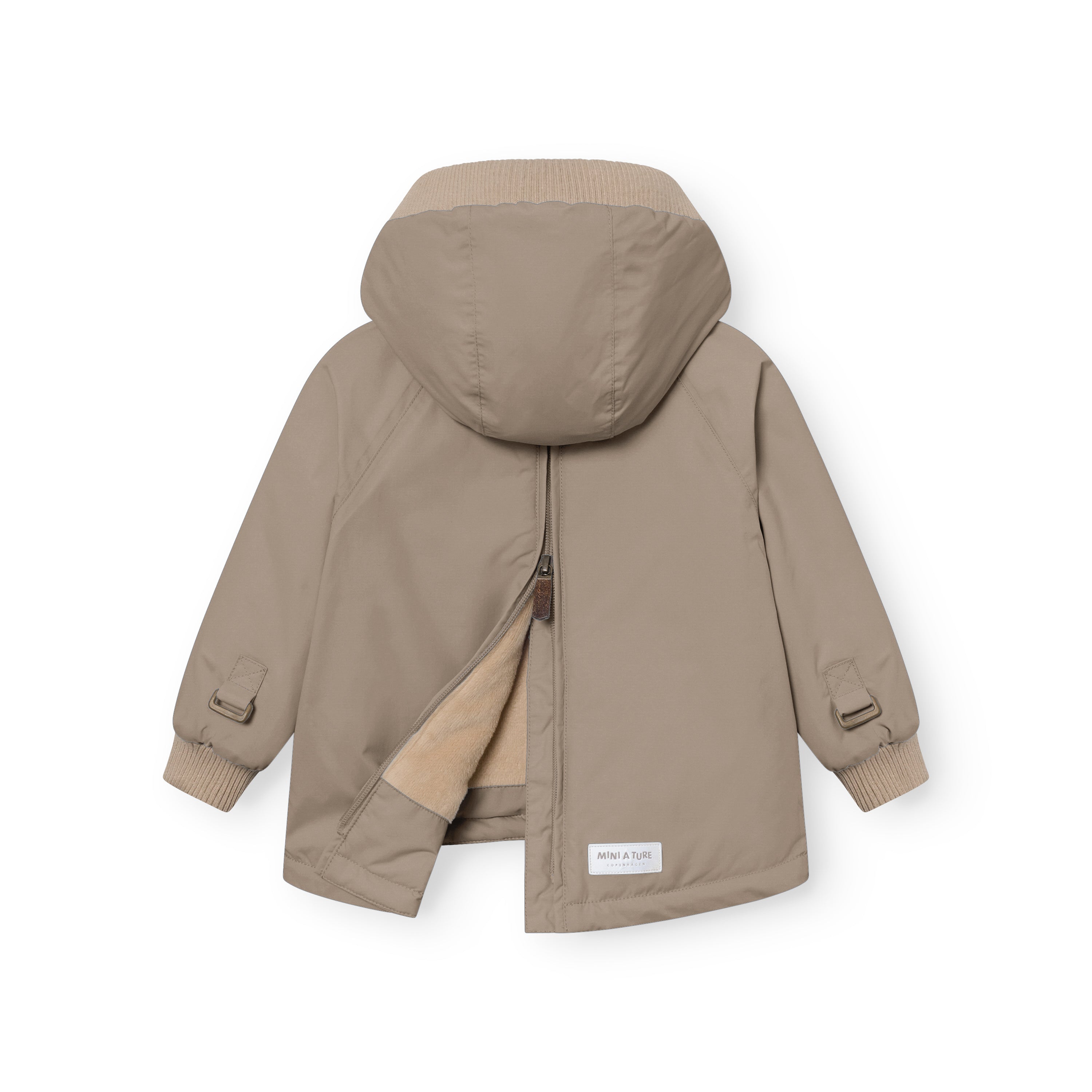 MATBABYWEN anorak in soft beige viewed from the back with the full-length zip partially open, revealing the beige fleece lining and demonstrating the flat-opening design that allows the coat to be laid out for easier dressing, with raglan sleeves, adjustable wrist tabs with metal buckles, and a white MINI A TURE label visible at the lower hem above the central back vent.