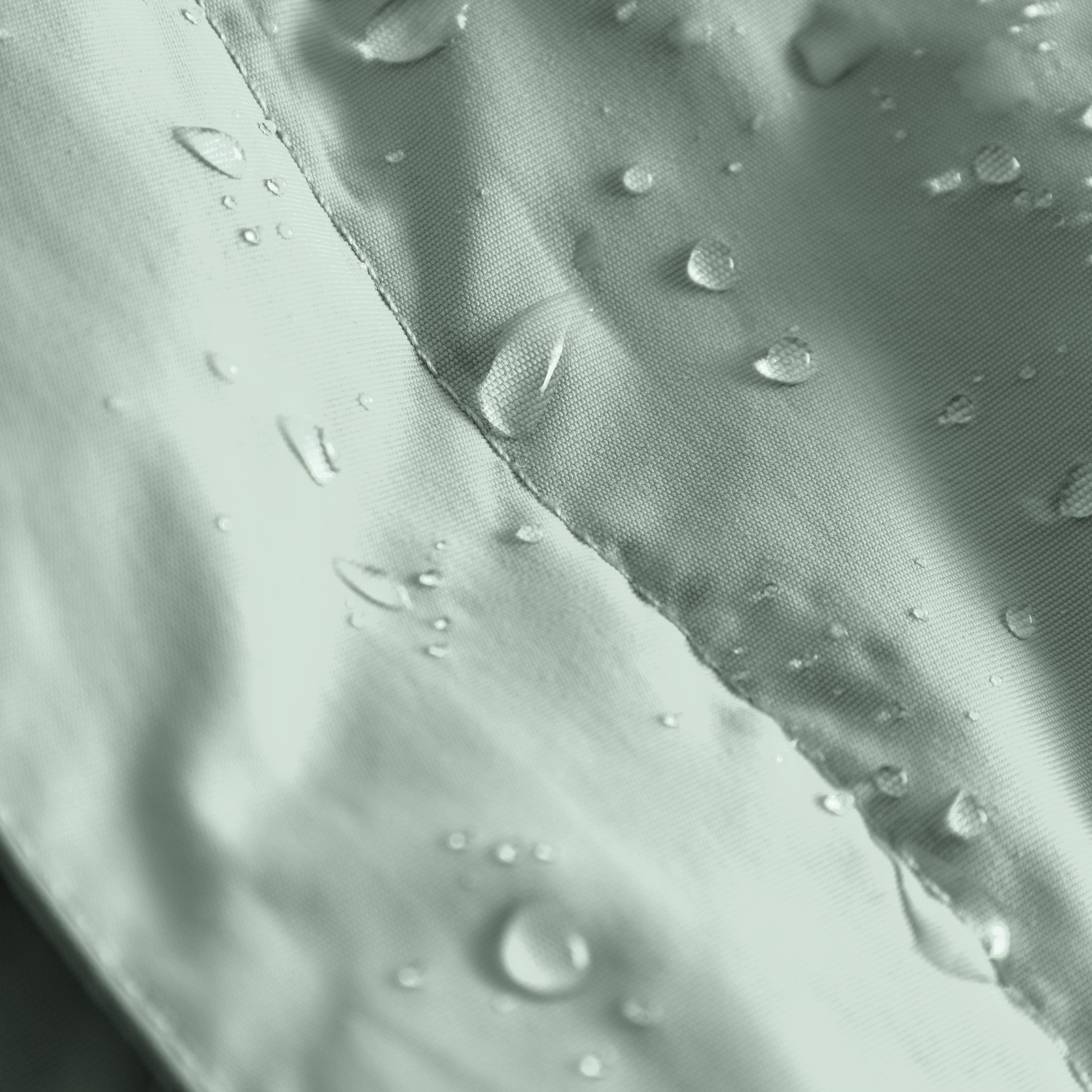 Close-up of the MATBABYWEN anorak in pale green showing water droplets beading on the recycled polyamide outer shell treated with fluorine-free Bionic Finish Eco, with a detailed view of the taped seam running diagonally across the waterproof fabric.