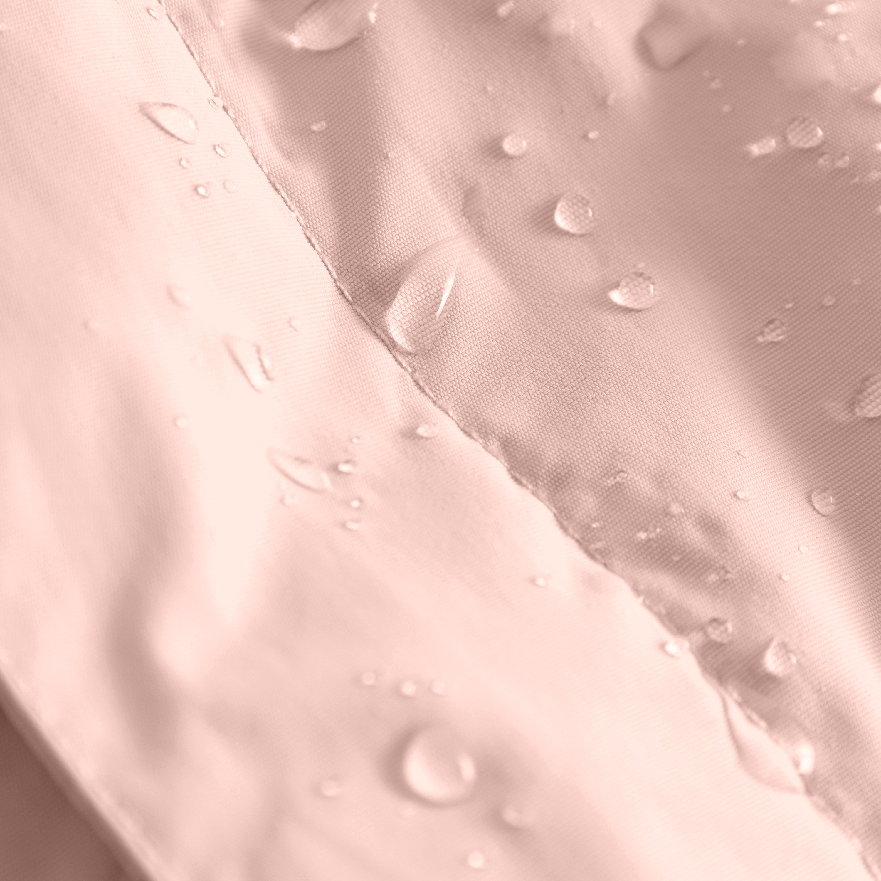 Close-up of water droplets beading on the surface of a pale pink waterproof children's jacket, demonstrating the water-repellent finish on recycled nylon fabric.