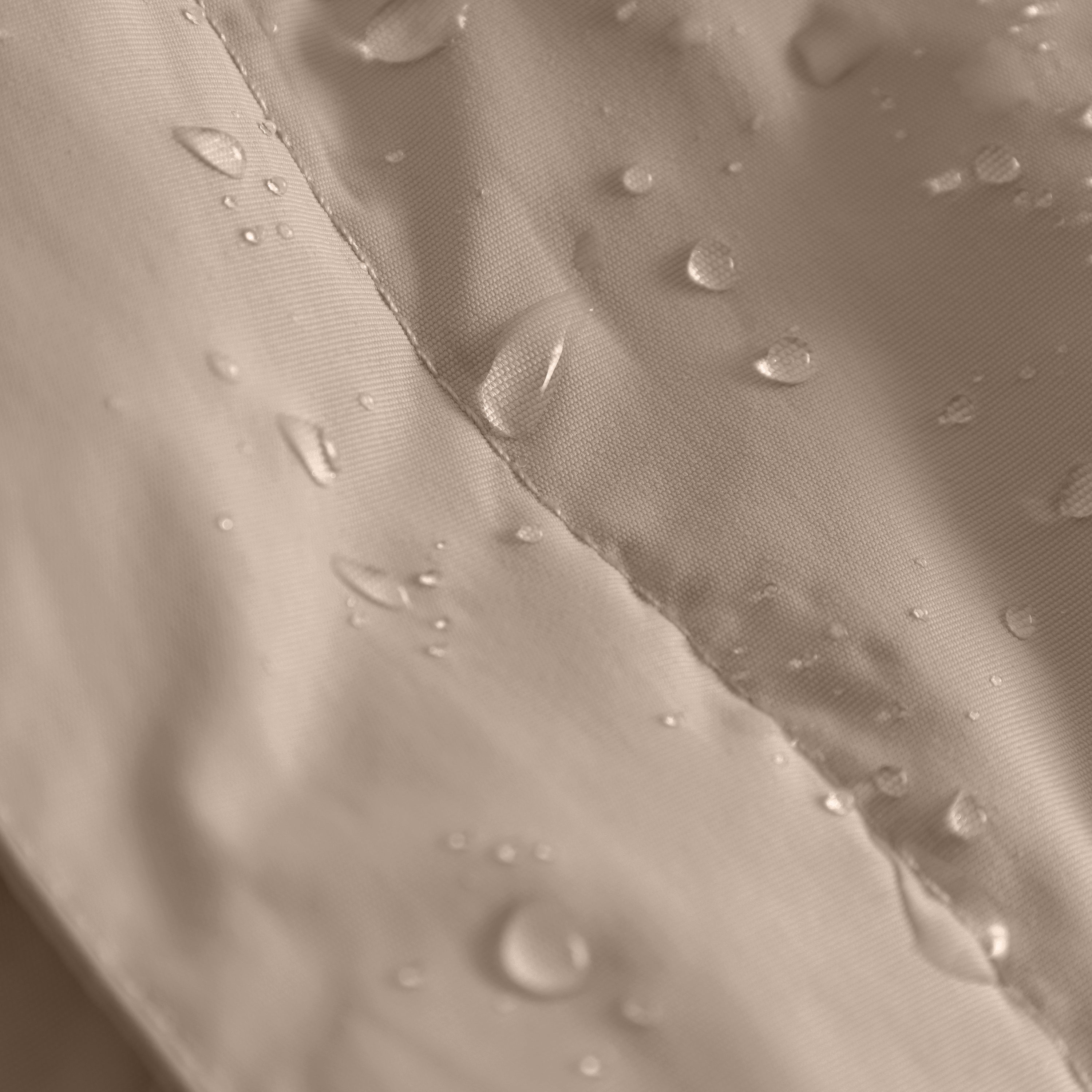 Close-up of water droplets beading on a waterproof recycled nylon shell fabric with taped seam construction, demonstrating the water-repellent treatment on a children's winter jacket.