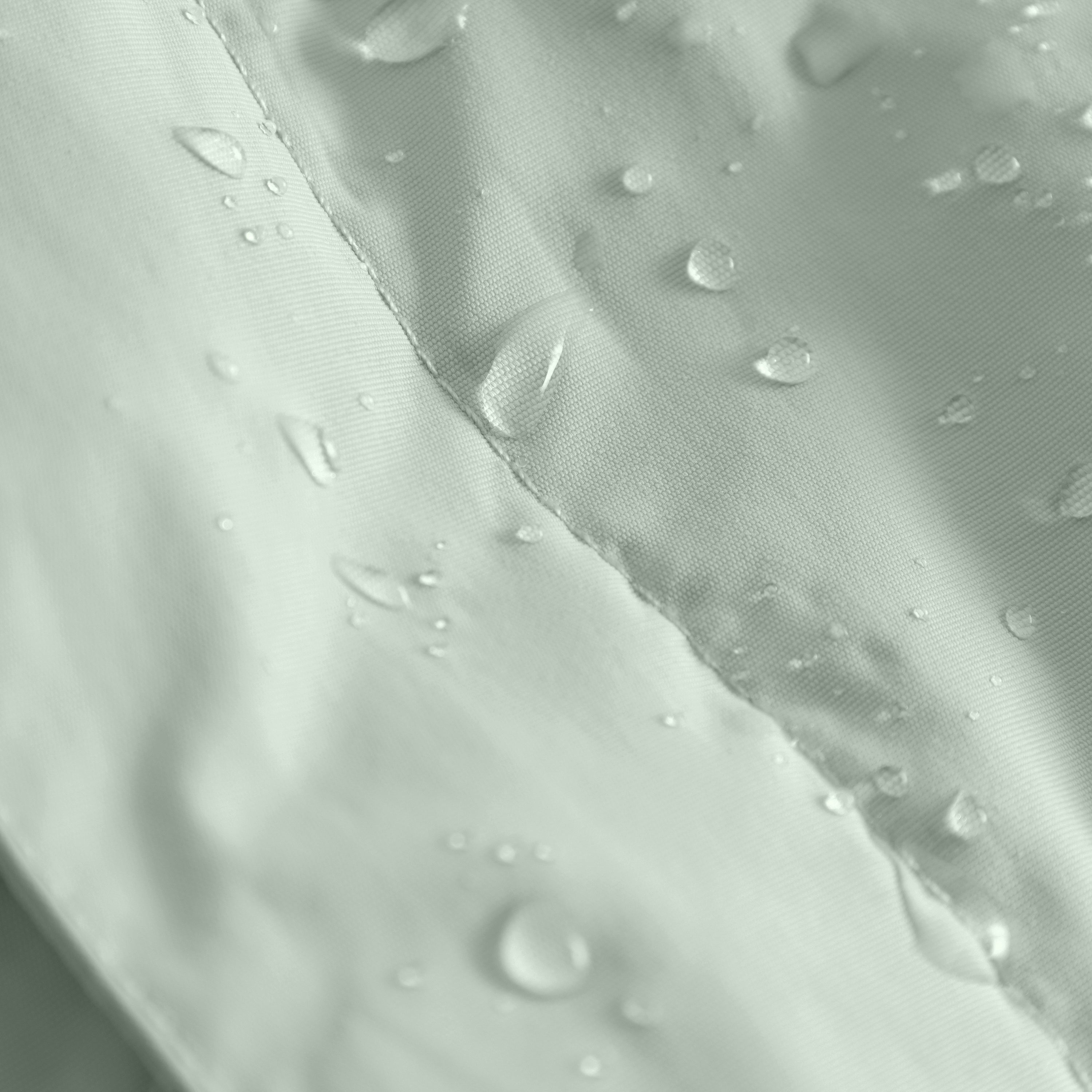 Close-up of the MATWANG fleece-lined winter jacket's recycled nylon shell with water droplets beading on the surface, highlighting the flat-felled seam construction and the water-repellent performance of the fluorine-free Bionic Finish Eco treatment in soft sage green.