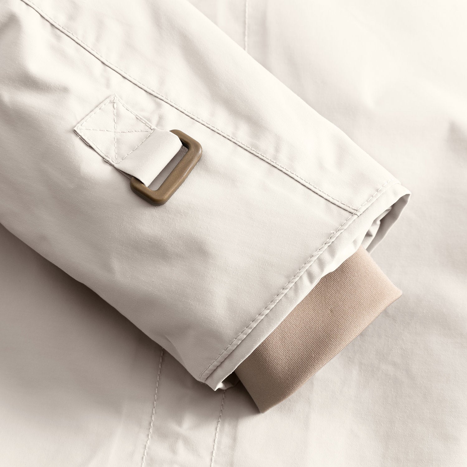 Detail of the MATWALLY fleece lined winter jacket sleeve in soft cream, showing the metal D-ring with fabric tab for snow cuff adjustment and the beige ribbed inner cuff with thumb opening visible at the hem.