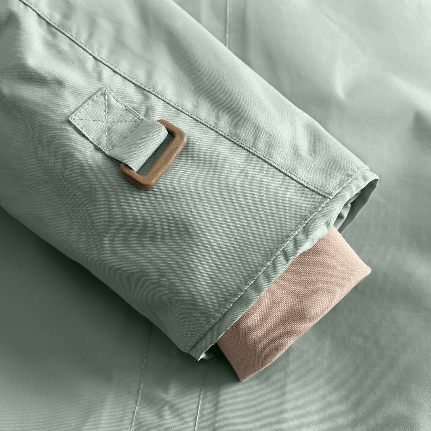 Detail of the MATWALLY fleece lined winter jacket sleeve in sage green, showing the adjustable snow cuff with metal D-ring and fabric tab, beige ribbed inner cuff extending below the outer sleeve and fully taped seam construction visible along the edge.