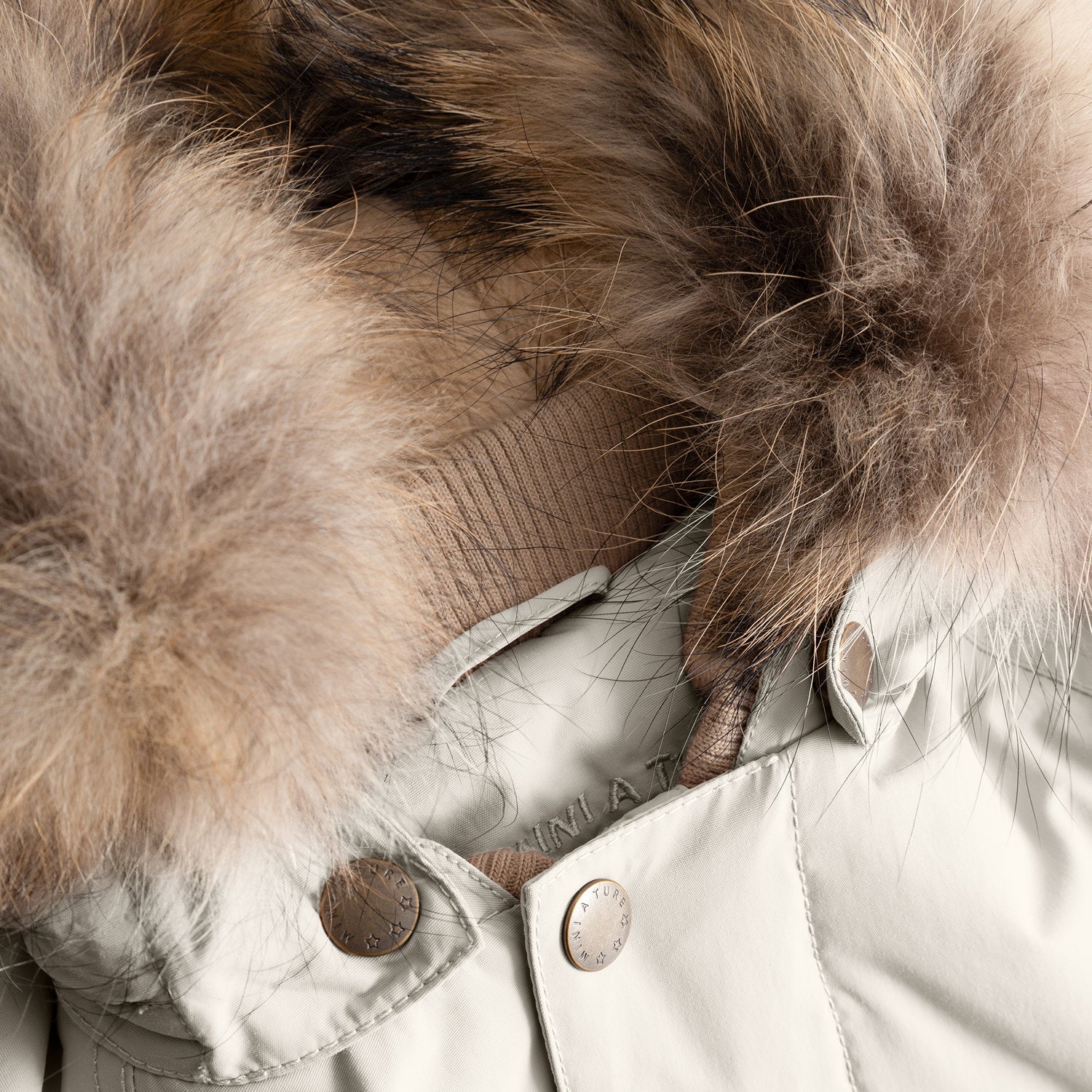Close-up of the MATWALLY fleece lined winter jacket's detachable real fur hood trim in soft beige, showing the hidden zip attachment system and branded press-stud hardware that allows the fur to be removed when not needed.