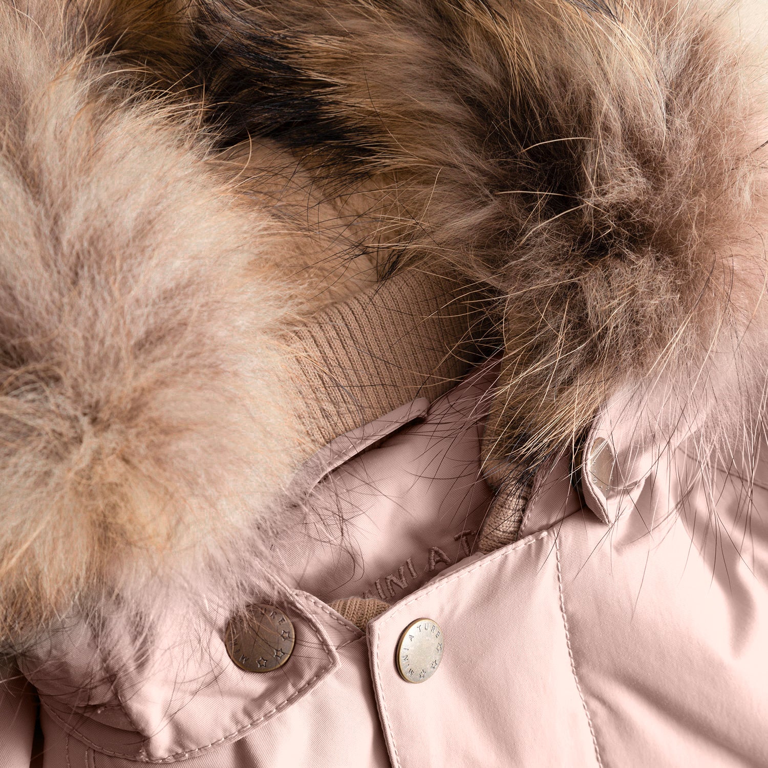 Close-up of the MATWALLY fleece lined winter jacket's detachable real fur hood trim in natural tones, showing the luxurious texture and density of the fur alongside the dusty pink outer shell, branded press-stud fastening, and the soft beige fleece lining visible at the collar edge.