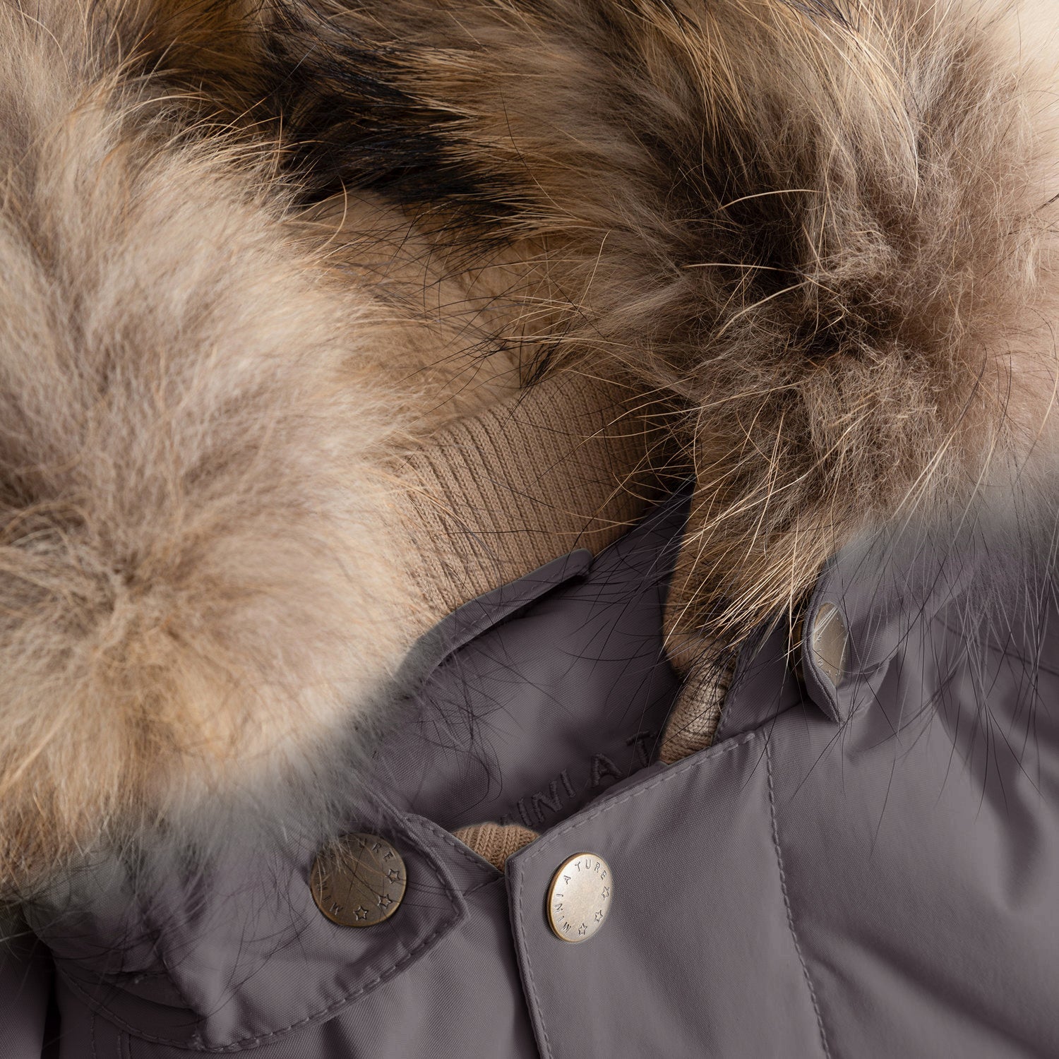 Close-up detail of the MATWALLY fleece lined winter jacket's detachable real fur hood trim in natural tones, highlighting the luxurious texture of the fur, the branded press-stud fastening system, and the soft beige fleece lining visible beneath the hood's edge.