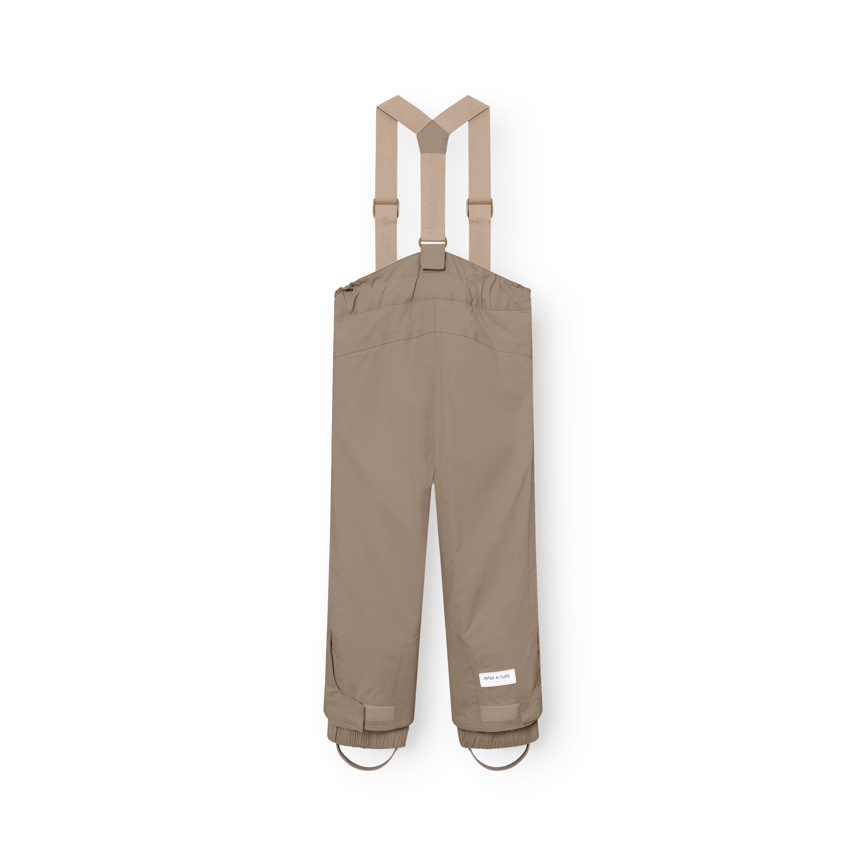 MATWITTE snow pants in warm beige viewed from the back, showing the cross-back elastic suspender configuration, elasticated ankle cuffs with integrated foot straps, and the MINI A TURE label positioned above the reinforced lower leg.