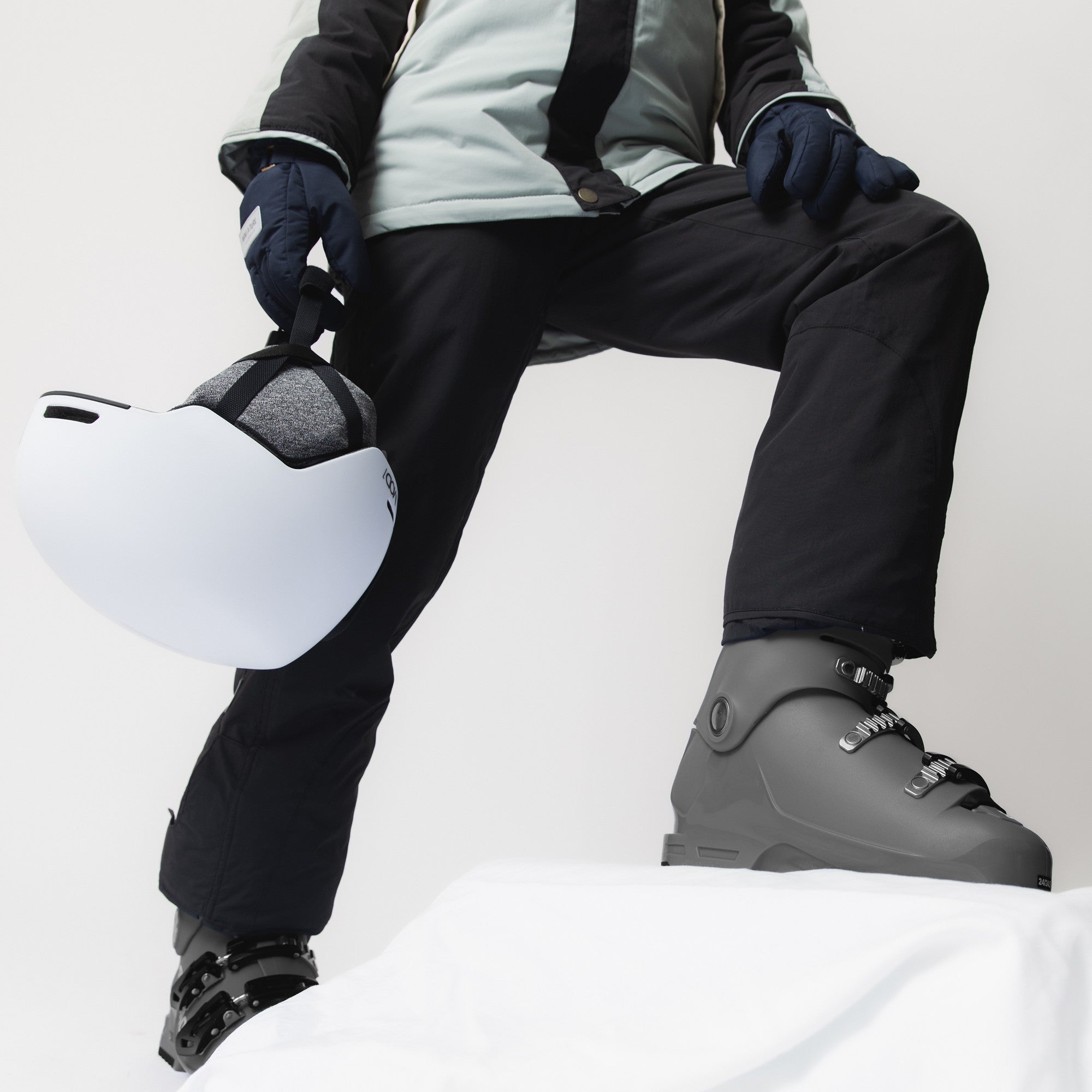 Child wearing MATWITTE snow pants in black with adjustable leg openings fitted over grey ski boots, showing the reinforced lower legs and hook-and-loop fastening designed to accommodate different boot sizes.