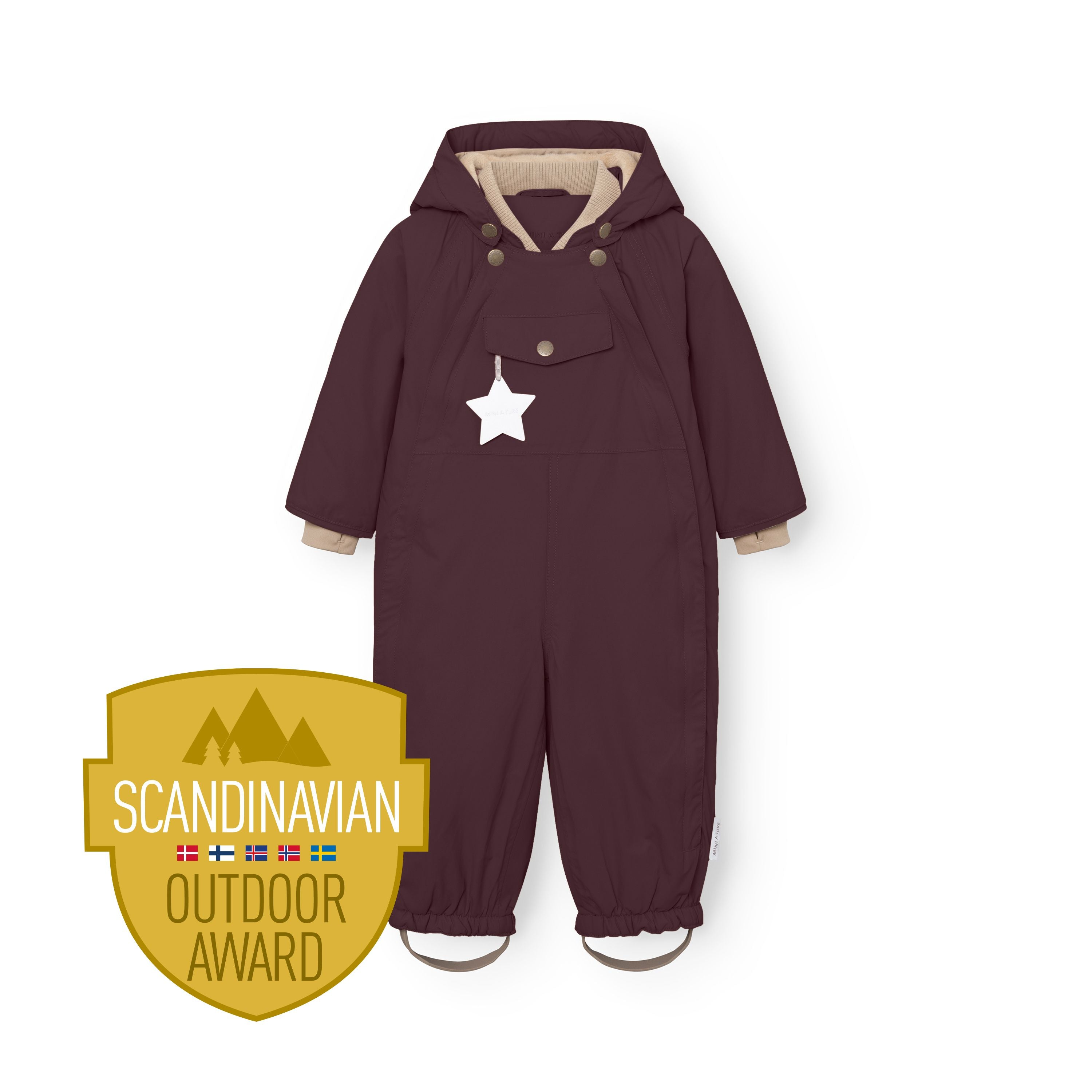Child standing in snowy woodland wearing the MATWISTI fleece lined snowsuit in deep plum with a red knitted beanie, arms raised and mittens visible, with the Scandinavian Outdoor Award badge displayed at the lower left.